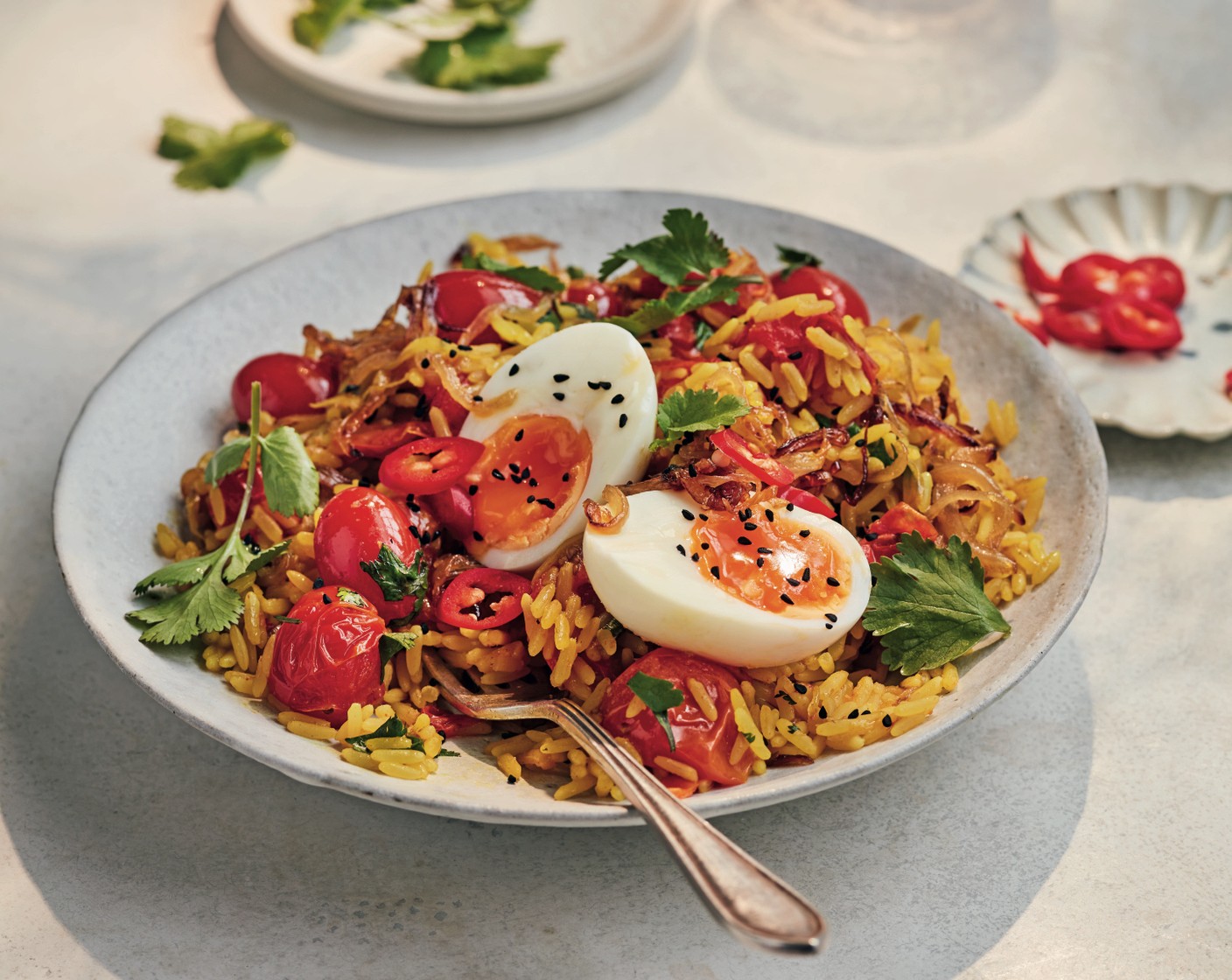 step 5 Divide the kedgeree between serving dishes and finish with the red chilli (1), coriander (1 handful), nigella seeds (1 tbsp) and eggs.