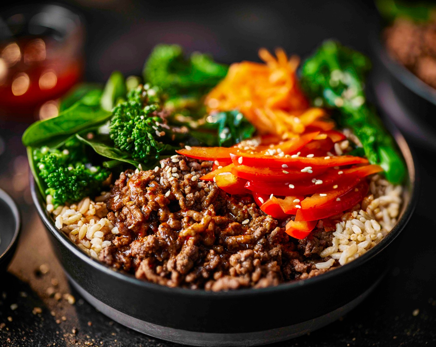 step 6 Spoon the rice into bowls. Top with the beef, broccoli, grated carrot (2) and sliced peppers (2). Drizzle over the sauce and scatter with sesame seeds (1 tbsp).