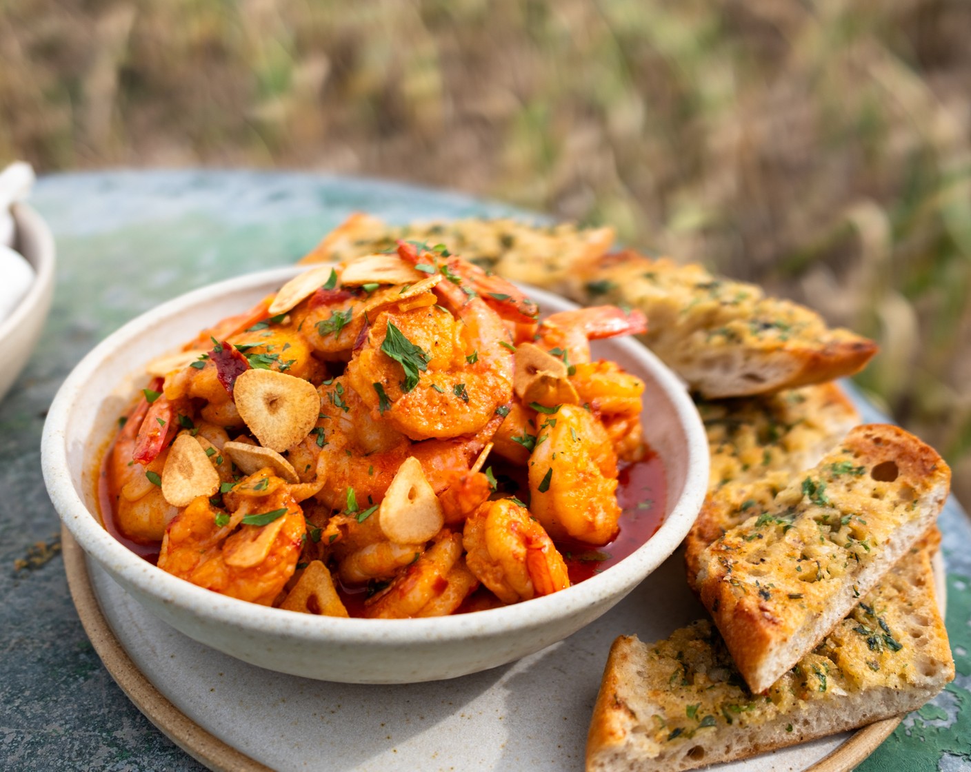 step 6 Remove the ciabatta from the oven and cut each half into 2-inch slices. Spoon the prawns into 2 serving bowls and sprinkle with the garlic chips and parsley (10 g). Serve the garlic toasts alongside for dipping.
