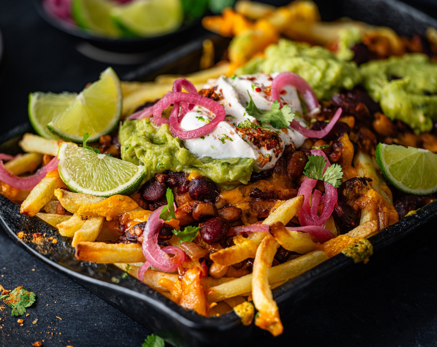 step 6 Serve the loaded fries with the spiced lime yogurt, coriander leaves (10 g), pickled red onions (20 g), guacamole (1 tub) and lime wedges.
