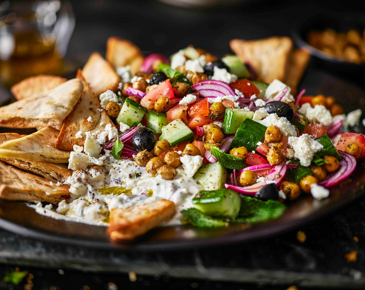 step 4 To assemble, lay the pitta chips on a large platter. Blob over the dip (1 tub), then top with the salad. Finish with the chickpeas, crumble over the Greek salad cheese (100 g) and some more fresh mint leaves.
