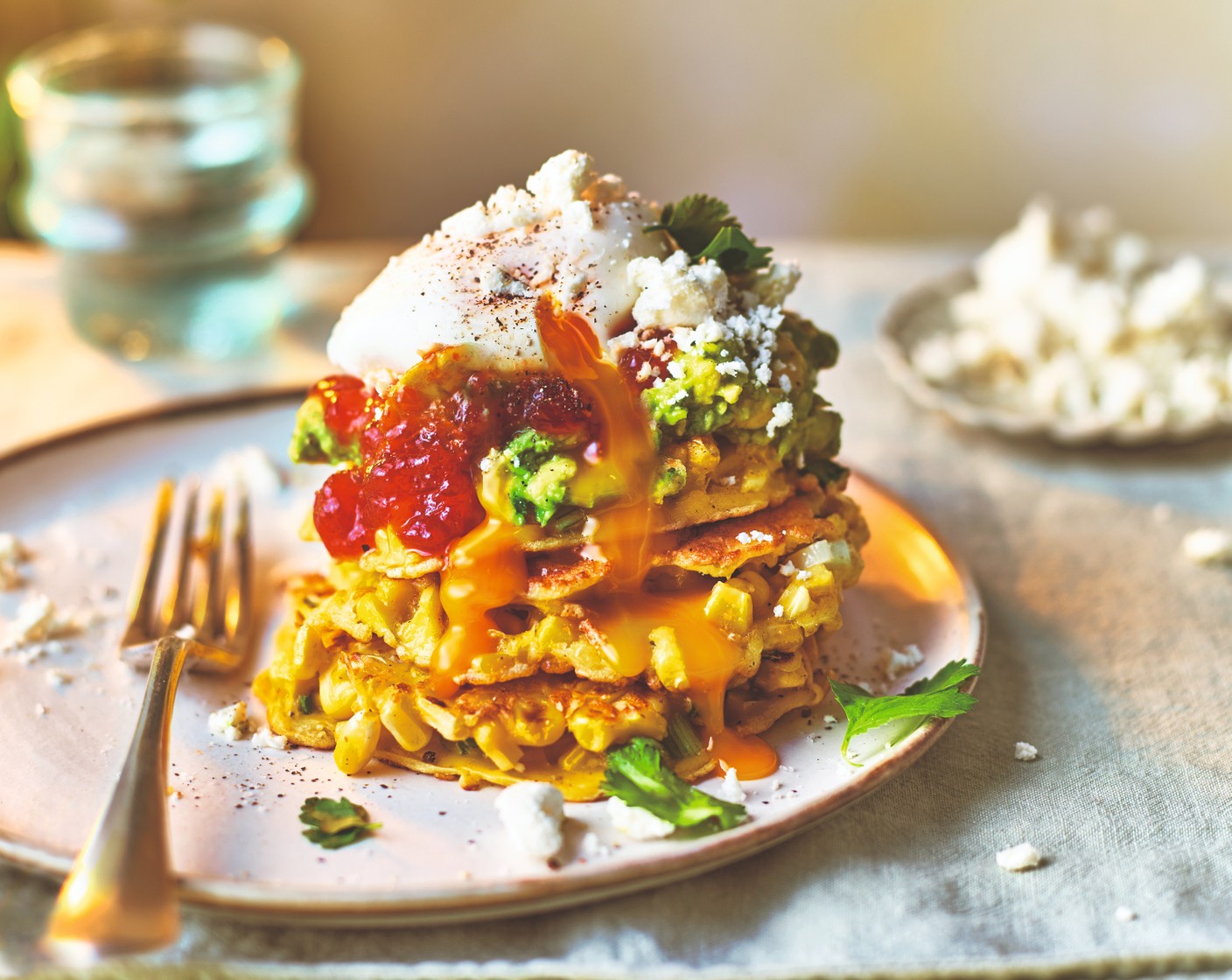 step 5 Arrange the fritters into four stacks. Top each stack with the smashed avocado, chilli jam (2 tbsp) (if using), a poached egg, crumbled feta (40 g) and coriander leaves (1 handful).