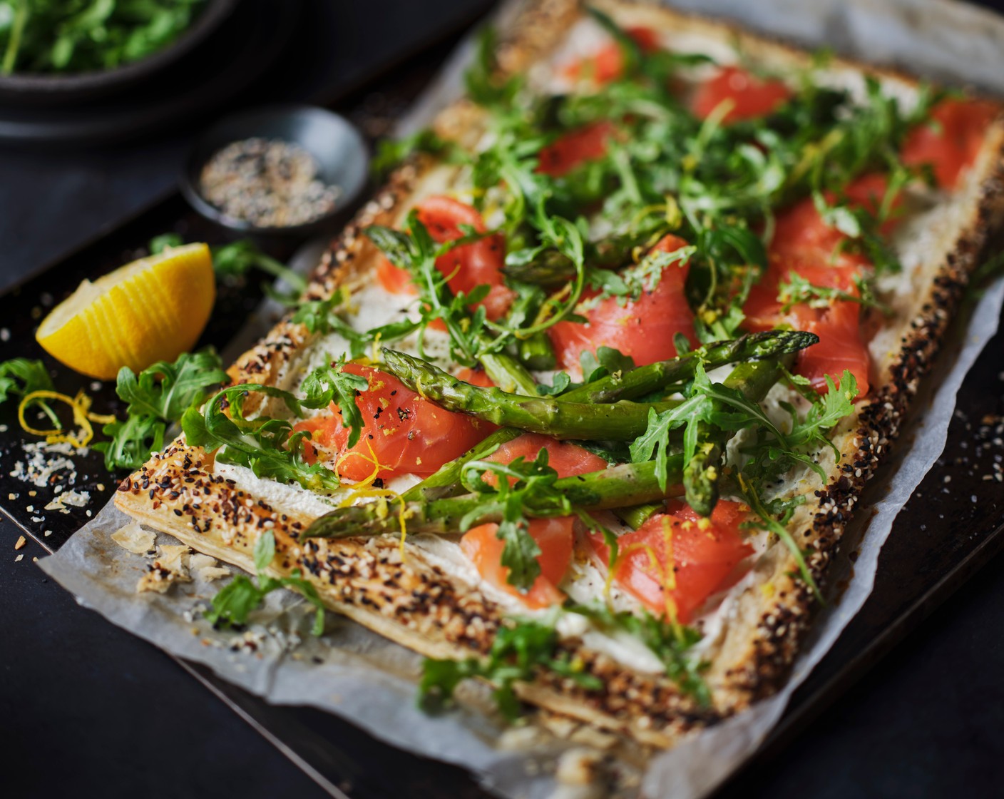 step 5 Spread the cream cheese mix onto the cooled pastry in the centre. Toss the rocket (80 g) in the honey and mustard dressing (1 tbsp). Dress the tart with the asparagus, followed by the trout (100 g), torn into smaller pieces. Top with the rocket and the lemon zest, and a generous amount of cracked black pepper.