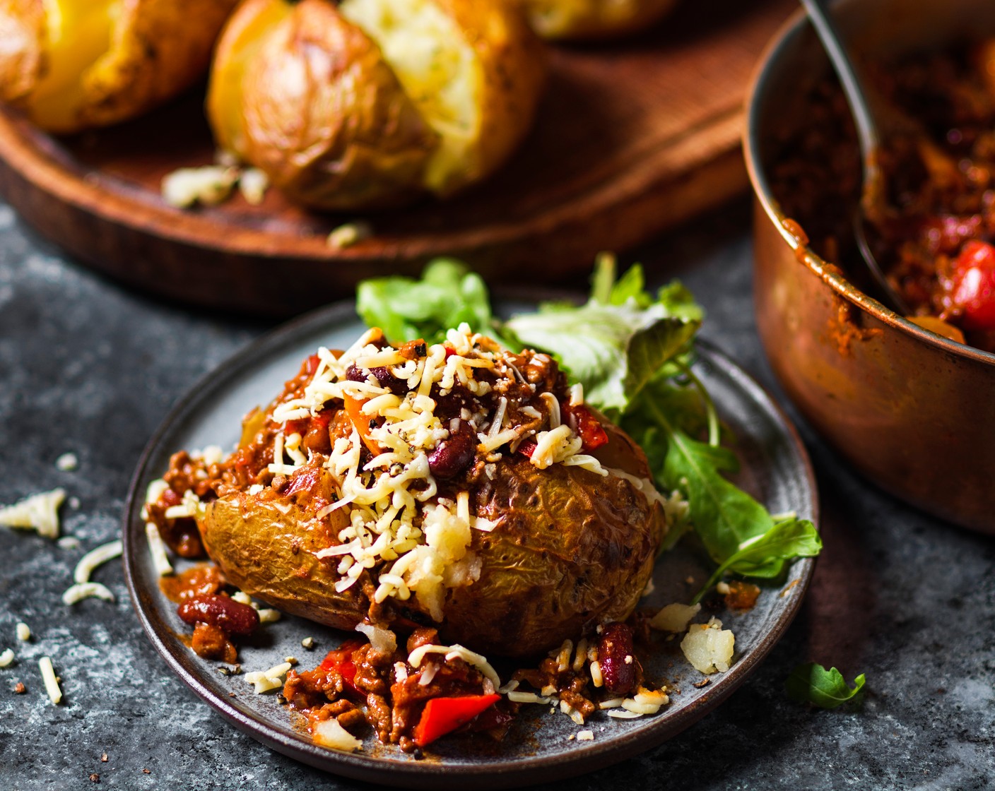 step 5 Cut open your hot jacket potatoes, spoon over the chilli con carne and sprinkle with plenty of cheddar (120 g).
