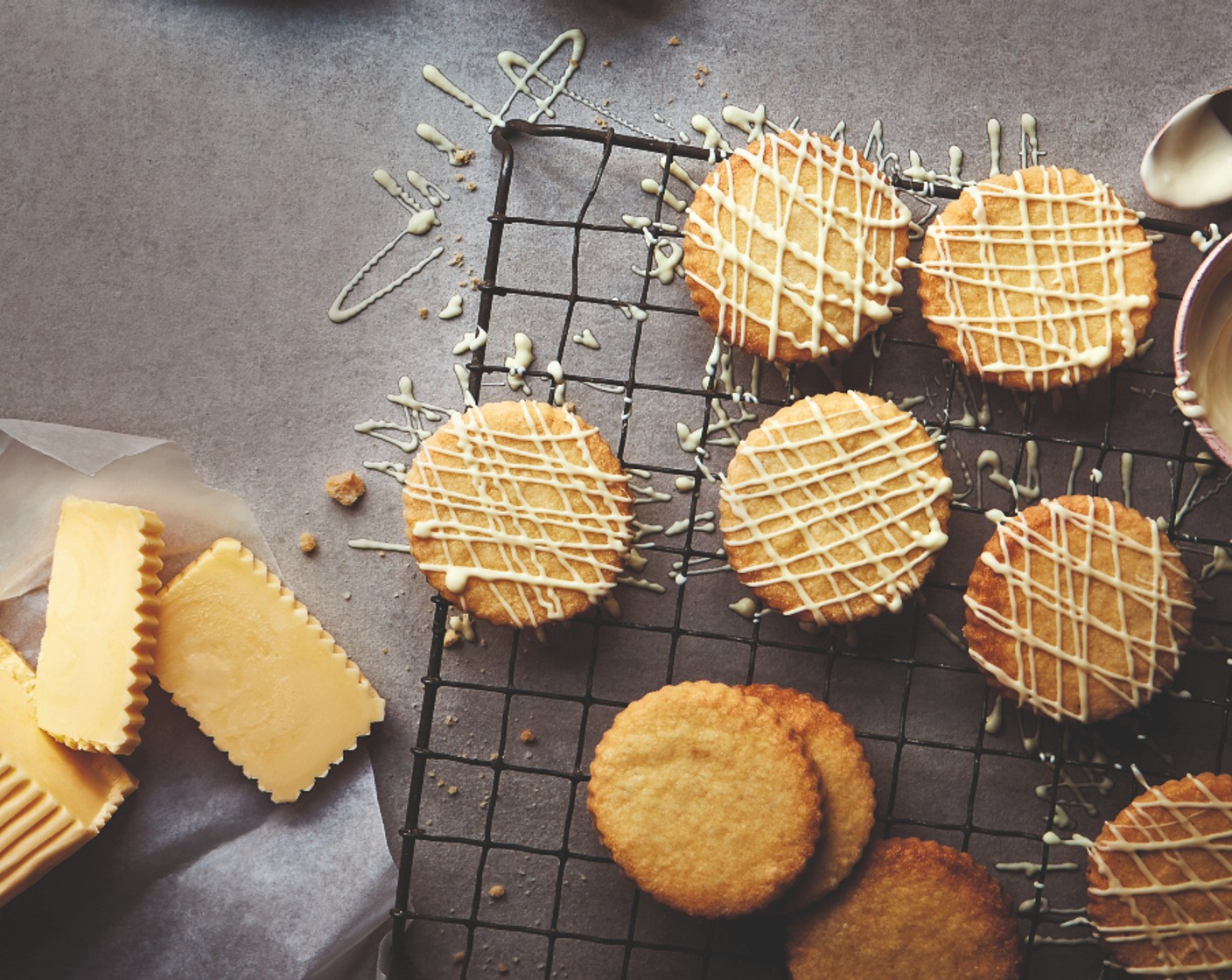 step 6 Meanwhile, melt the white chocolate (100 g) in a heat-proof bowl over a saucepan of simmering water. When the biscuits are ready, decorate them in criss-cross patterns. Allow to cool.