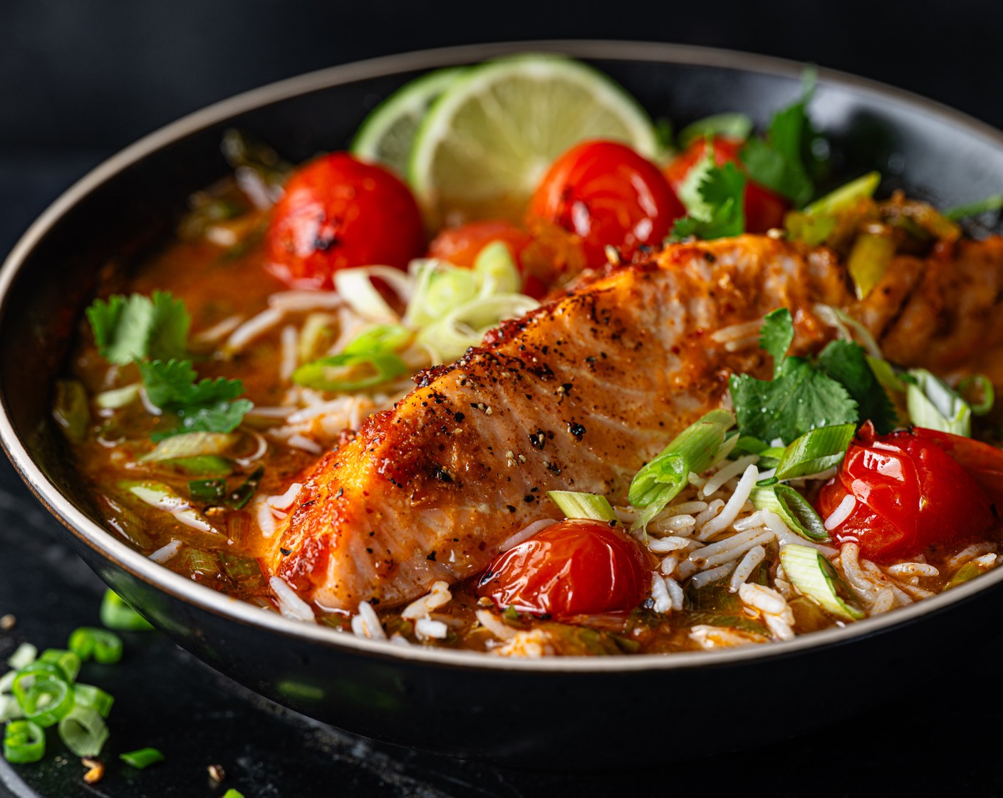 step 7 Top the brothy rice with the grilled salmon, scatter with fresh coriander (10 g) and serve with lime wedges (1/2).