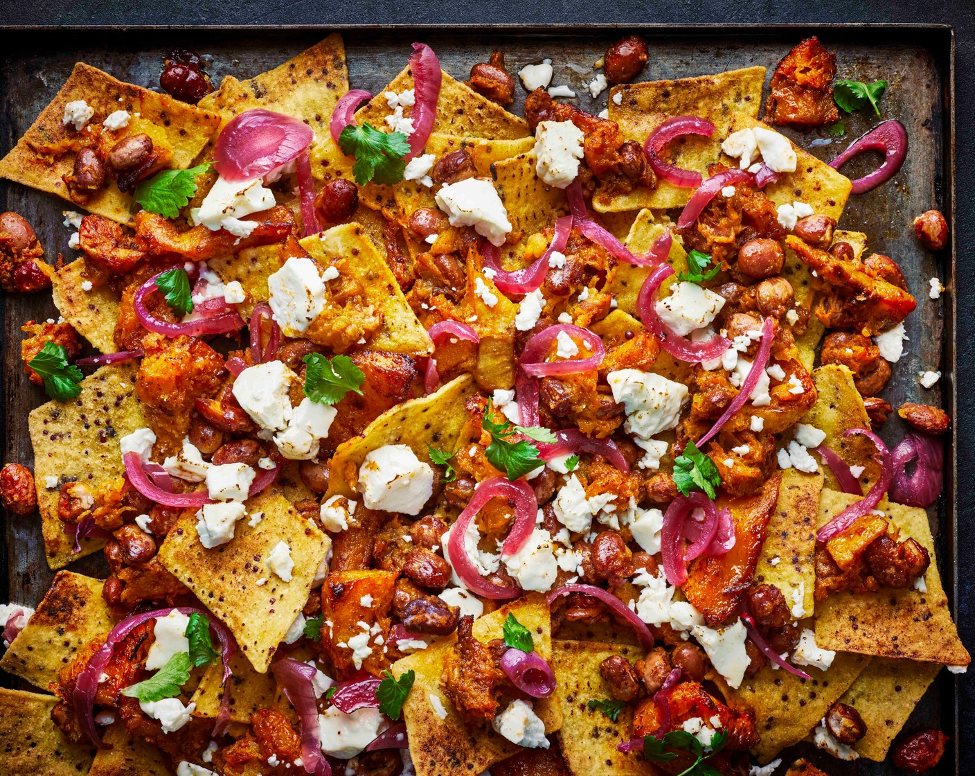 step 3 Lightly mash the butternut squash with the beans. Add the nachos (1 pack) to a large baking tray, top with the lightly mashed squash and beans and scatter over the pickled red onions (4 tbsp) and feta (100 g). Return to the oven for 5 mins, until lightly charred, and then top with the remaining coriander leaves to serve.