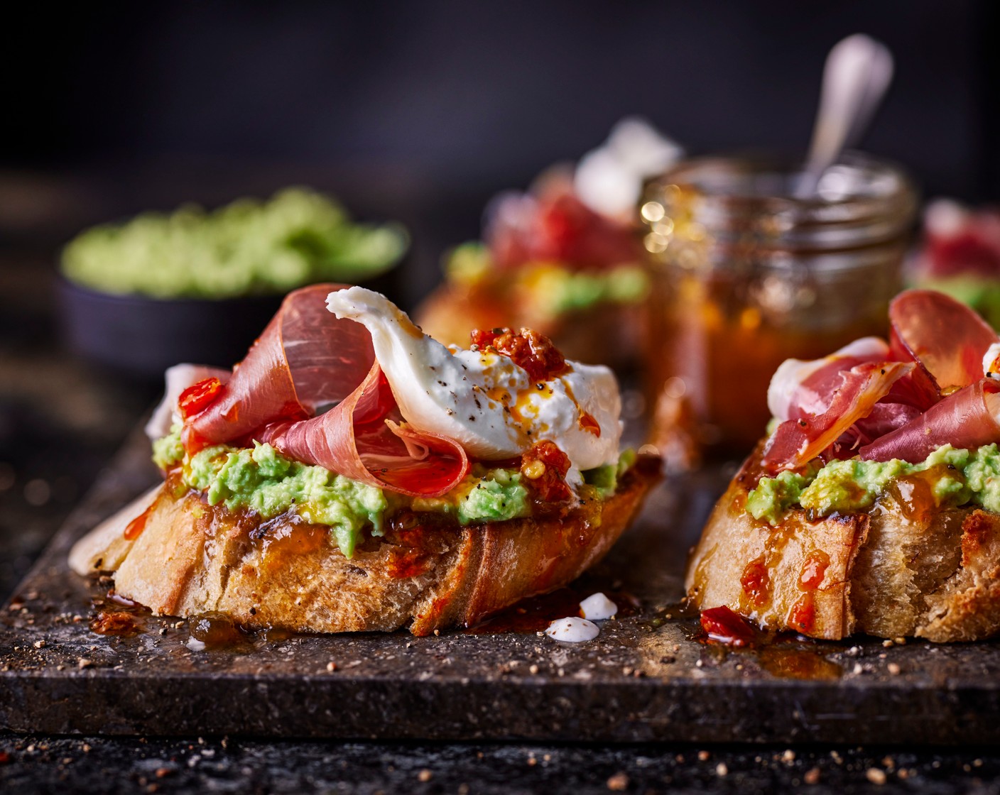 step 4 Spread the relish (3 tbsp) onto the bread slices, followed by the broad bean smash, serrano ham (70 g) and bocconcini (1 pack). Drizzle with the Calabrian chilli paste (to taste), if you’d like.