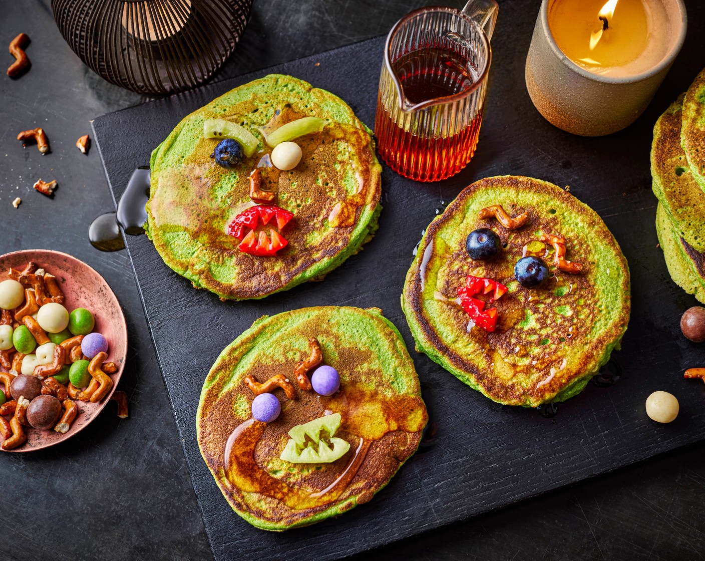 step 4 Decorate the pancakes to look like monsters using the hallow-scream munch (1 handful) and blueberries (100 g) as eyes, noses and ears, and the kiwis (1) and strawberries (100 g) cut to look like sharp teeth. Serve with maple syrup (to taste) and yogurt (to taste), if you like.