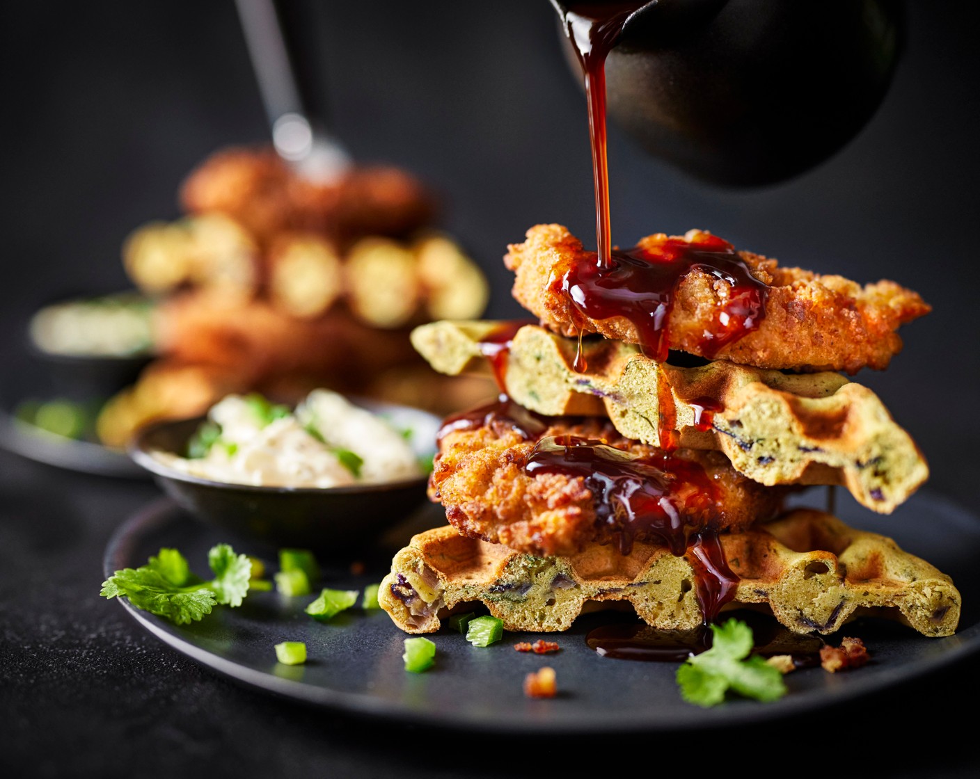 step 8 To serve, pour a bit of glaze into the bottom of a bowl. Halve the waffles into triangles and stack them on top of each other. Top with the buttermilk chicken and pour over a bit more glaze. Serve with a sprinkling of coriander and with the jalapeño crème fraîche on the side.