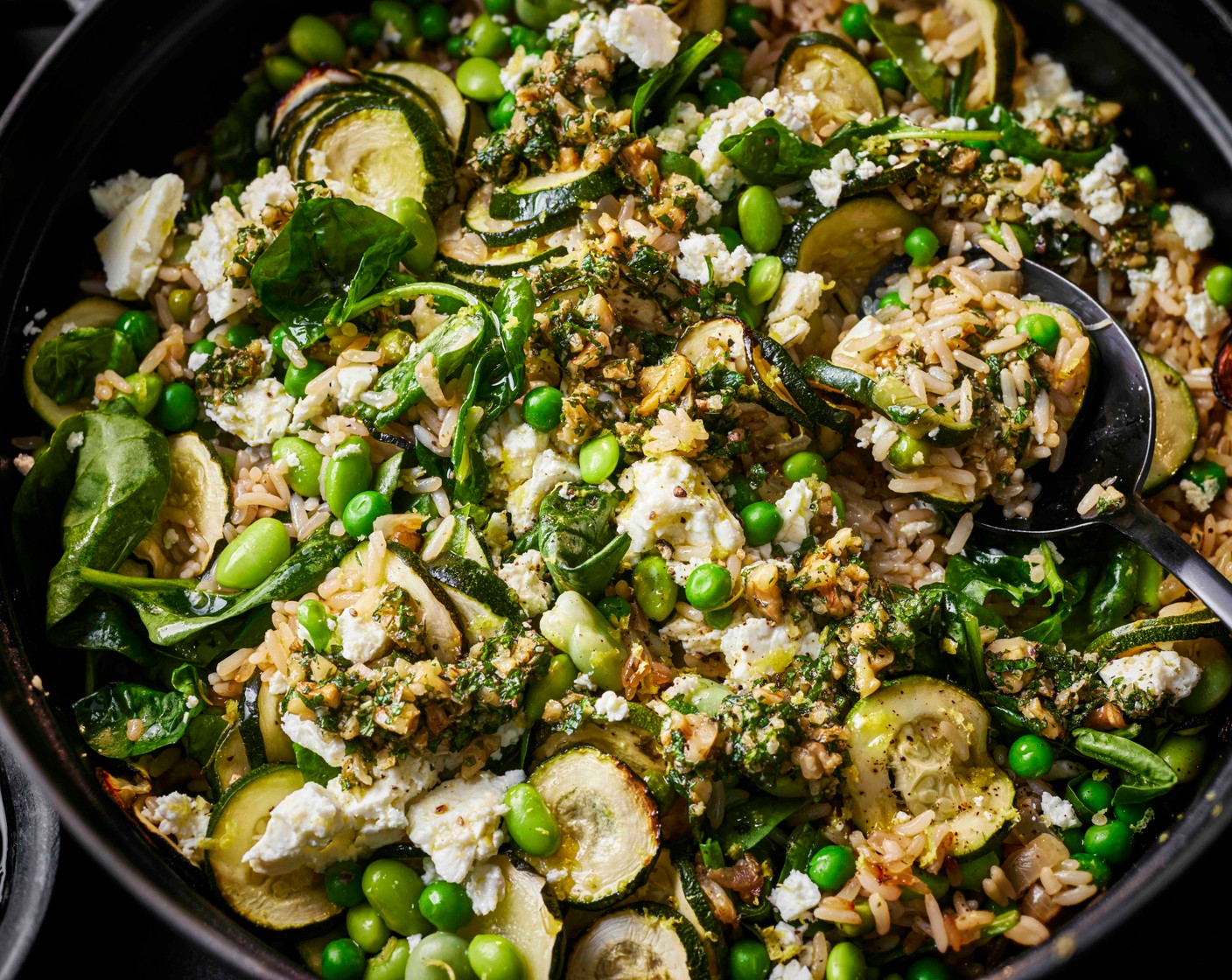step 5 Fluff the baked rice with a fork and stir through the lemon zest, spinach (40 g) and half of the feta (200 g). Serve topped with the remaining feta and a spoonful of the mint and walnut pesto.