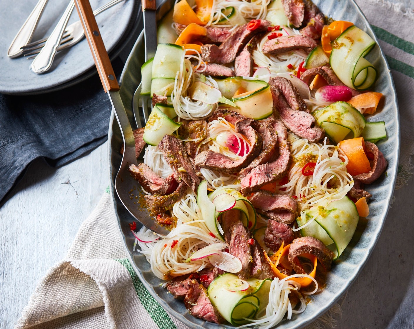 step 5 Toss the radish (80 g), cucumber (170 g), carrot (1) and red chilli (1) in a large bowl with the dressing and cooked noodles. Tumble onto a platter. Slice the steak into thin strips and arrange on top of the noodles and veggies.