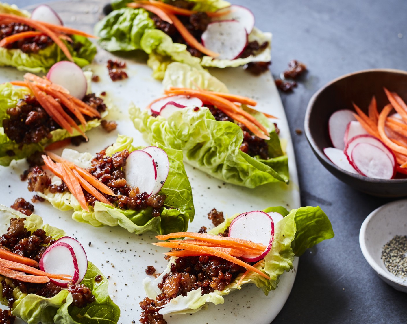 step 3 Prepare the lettuce cups by adding a spoonful of the fried pork mixture to each one and dividing the carrot strips (1) and sliced radishes (4). Serve with sweet chilli sauce (to taste), if liked.