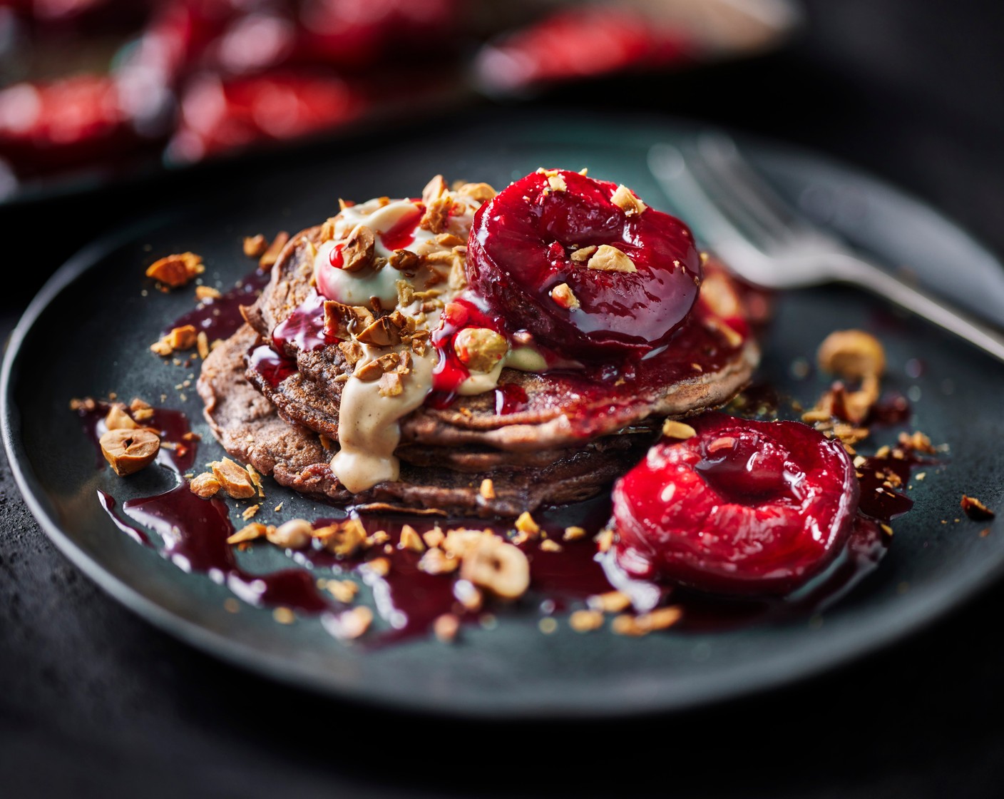 step 5 Top the pancakes with the yogurt (150 g), followed by the roasted plums, hazelnut creme and the hazelnuts (as needed).