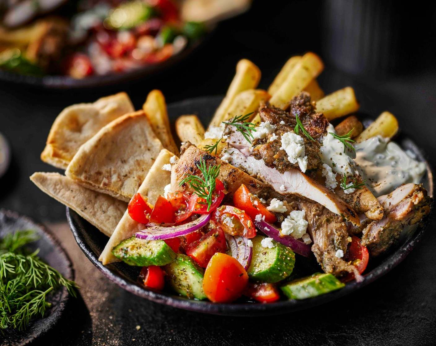 step 6 Divide the salad between four bowls, then add the chicken, chips and a dollop of tzatziki (as needed). Crumble over the feta (80 g) and sprinkle with a bit of dill (1 handful). Serve each with the flatbread slices and a lemon wedge (1), for squeezing.