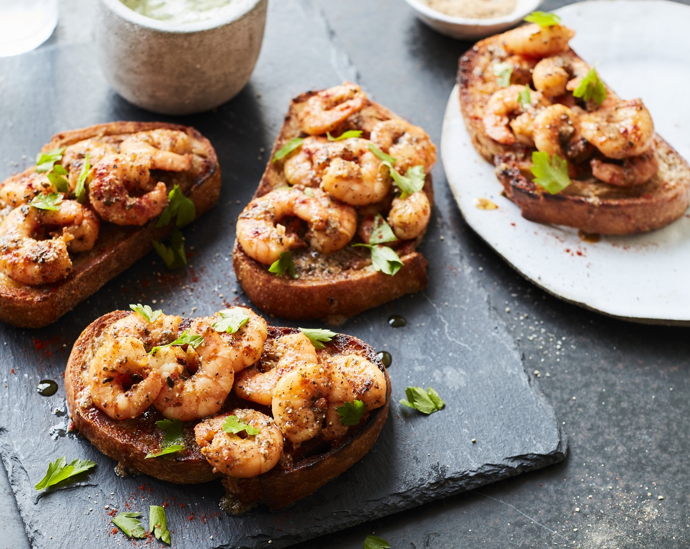 step 4 Spoon the prawns (along with their cooking liquor) over the slices of chargrilled sourdough. Dust with smoked paprika (to taste) and scatter over some flat leaf parsley (as needed) to garnish.