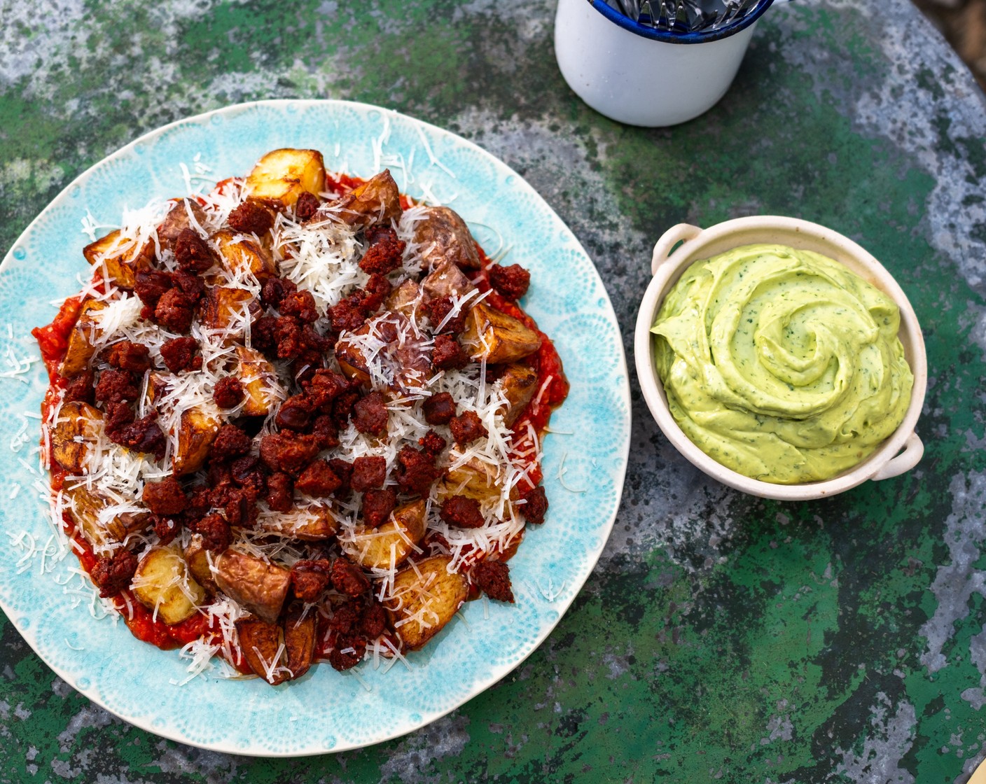 step 6 Serve by spreading the spicy tomato sauce onto the base of your serving plate. Top with the crispy potatoes. Sprinkle over the grated Manchego cheese (50 g) and then the crispy chorizo to serve. Spoon the avocado crema into a bowl to serve alongside.