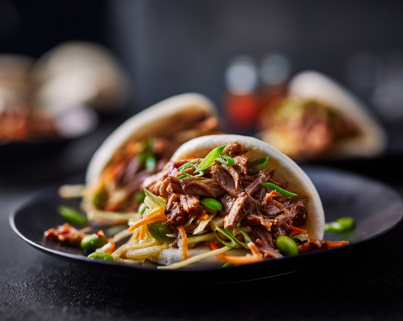 step 4 Shred the pork with two forks and fill the bao buns with the pork and slaw. Top with the spring onions (2), and some chilli sauce (to taste) if you like.