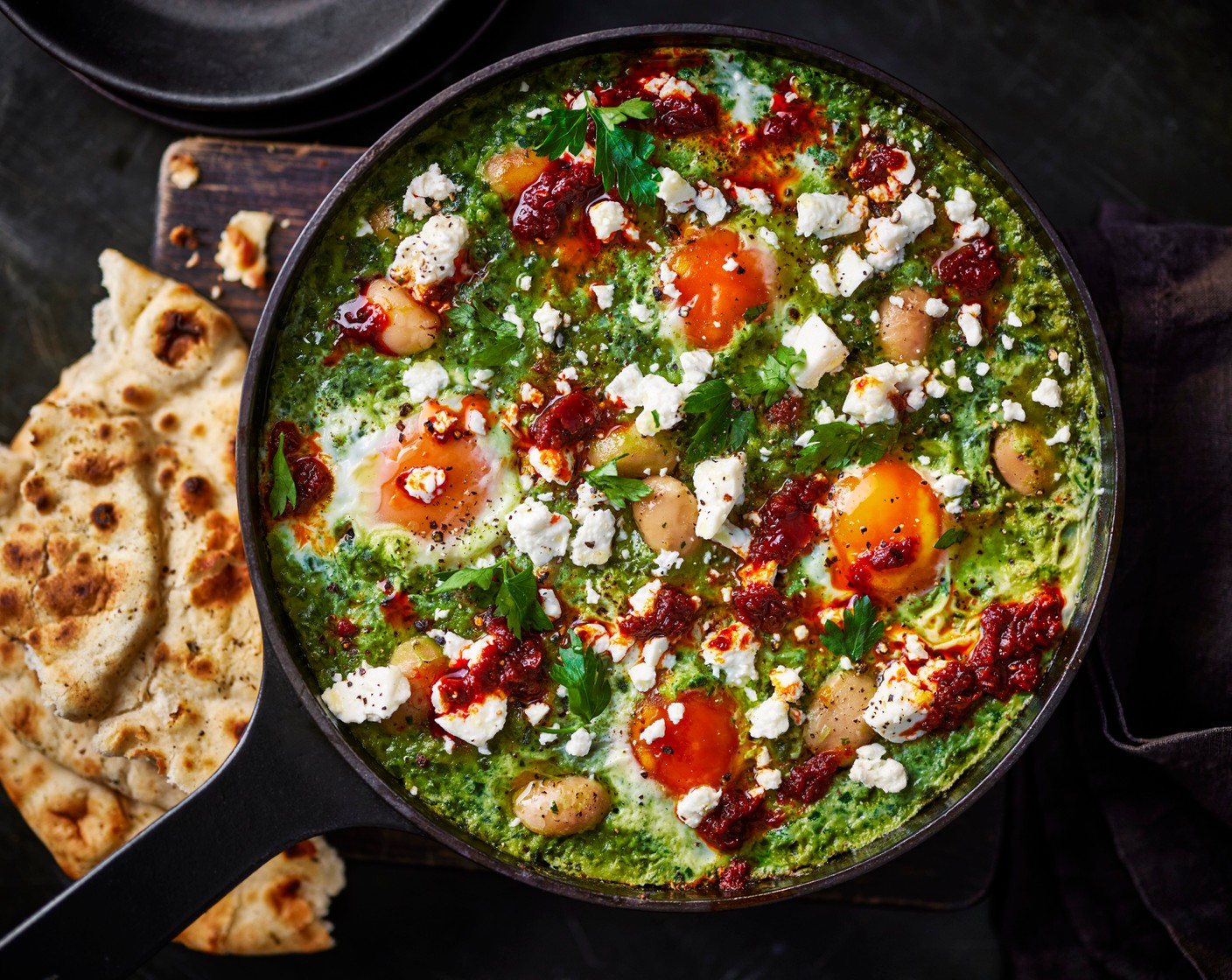 step 5 Once the eggs are cooked, crumble the feta (50 g) over the eggs and scatter over the remaining parsley (10 g) and drizzle with the harissa (1 tbsp). Serve with the flatbreads.