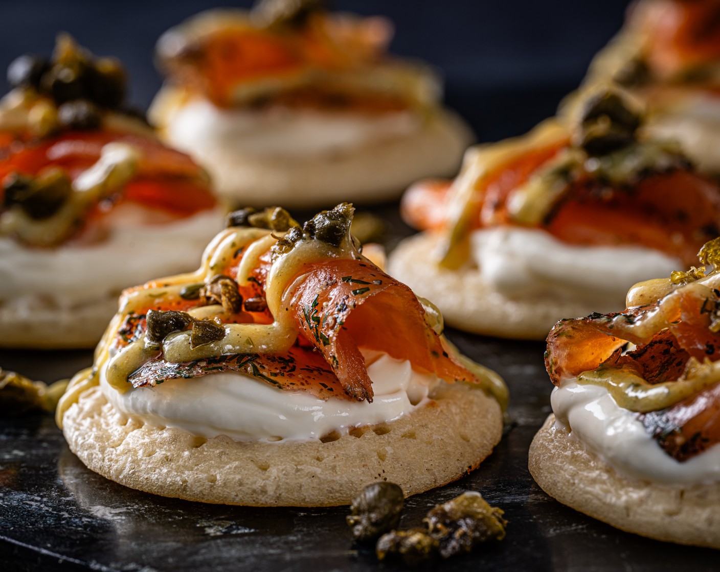 step 3 Top the blinis (16) with crème fraîche (16 tsp), gravadlax and dressing, then finish by scattering each with a pinch of capers.