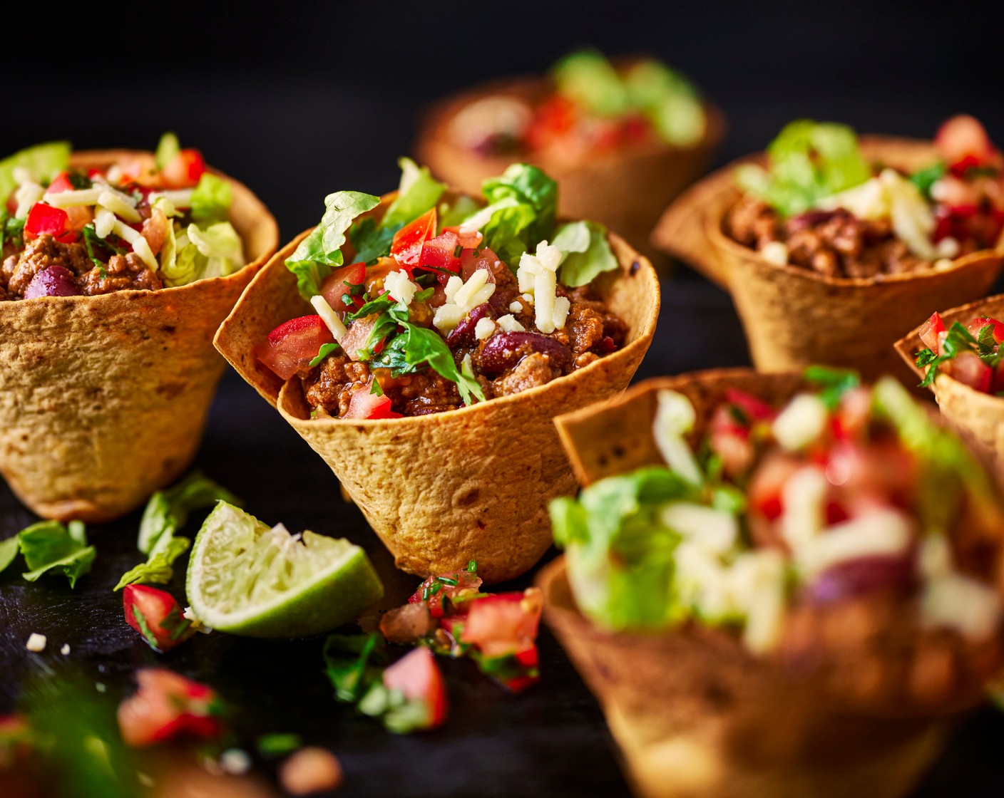 step 7 Serve the beef chilli in the taco cups along with the salsa, shredded lettuce and the leftover grated cheddar and coriander. Serve with the remaining lime (1), cut into wedges, on the side.