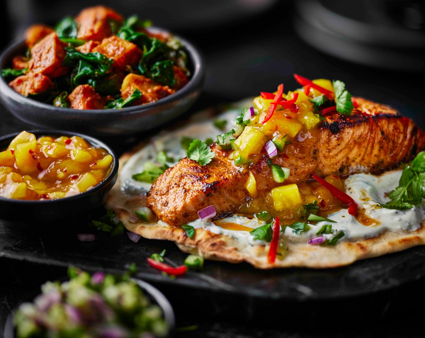 step 9 Spread the mint yogurt over the warm flatbreads and top with the salmon. Spoon over the mango chutney and cucumber salad. Scatter with sliced chilli (1) and coriander (10 g), and serve with the potatoes alongside.