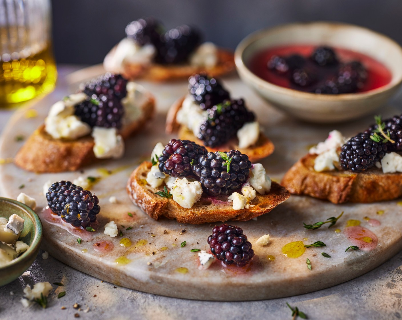 step 4 Crumble the goat's cheese (75 g) over the crostini and top with the blackberries, thyme (2 sprigs) leaves, some cracked black pepper and a drizzle of olive oil.