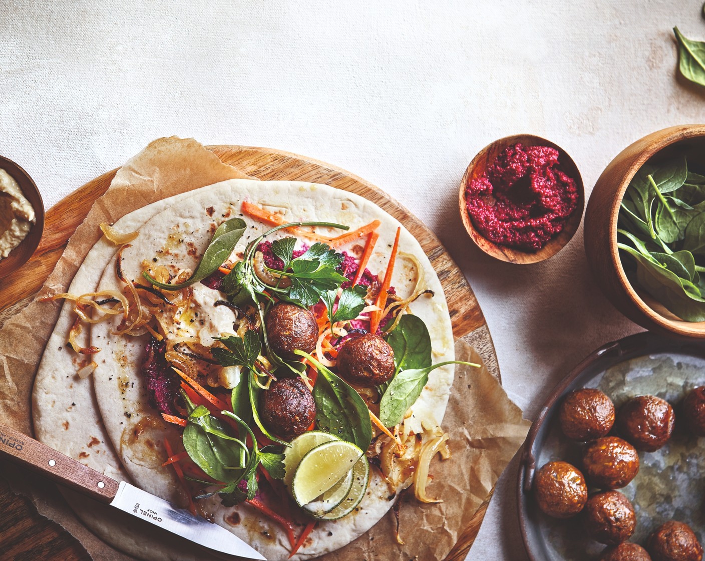 step 7 Assemble your wraps by smearing spoonfuls of houmous (1 pot) and beetroot dip over each of the warm piadinas. Top each one with shards of carrot, rocket (60 g) and three of the meatballs, then add the caramelised onions and a scattering of fresh parsley (1 bunch) before rolling up the wraps. Wrap some foil around the bottom of each wrap to prevent mess, if you like.