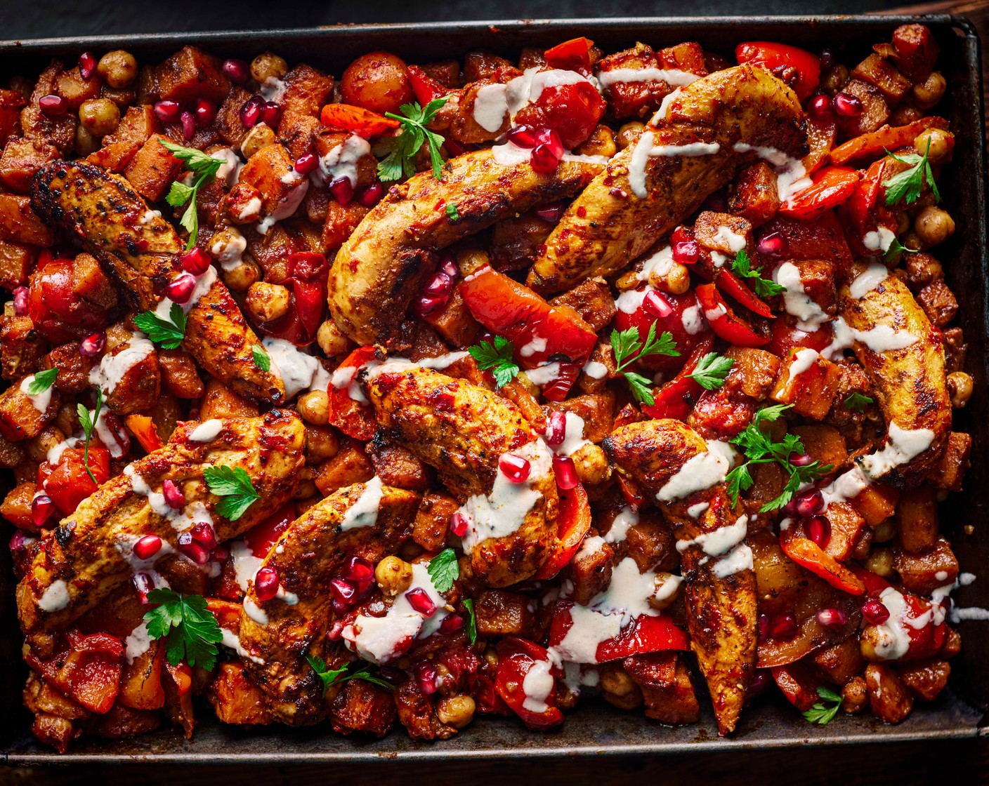 step 6 Once the chicken is cooked and the vegetables are tender, drizzle over the tahini and scatter over the parsley (15 g) and pomegranate rubies (4 tbsp).