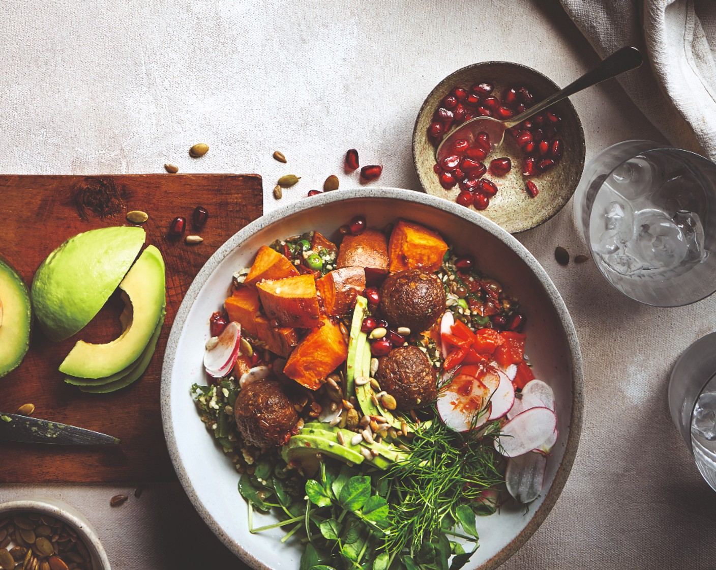 step 5 To assemble, spoon the grains into shallow bowls, then top with the sweet potatoes and veggie balls. Add the avocado, radishes (1 handful) and pea shoots (1 handful). Spoon over the dressing. Scatter over the pumpkin and sunflower seeds (1 handful), pomegranate seeds (1 handful) and fresh herbs (to taste), if using.