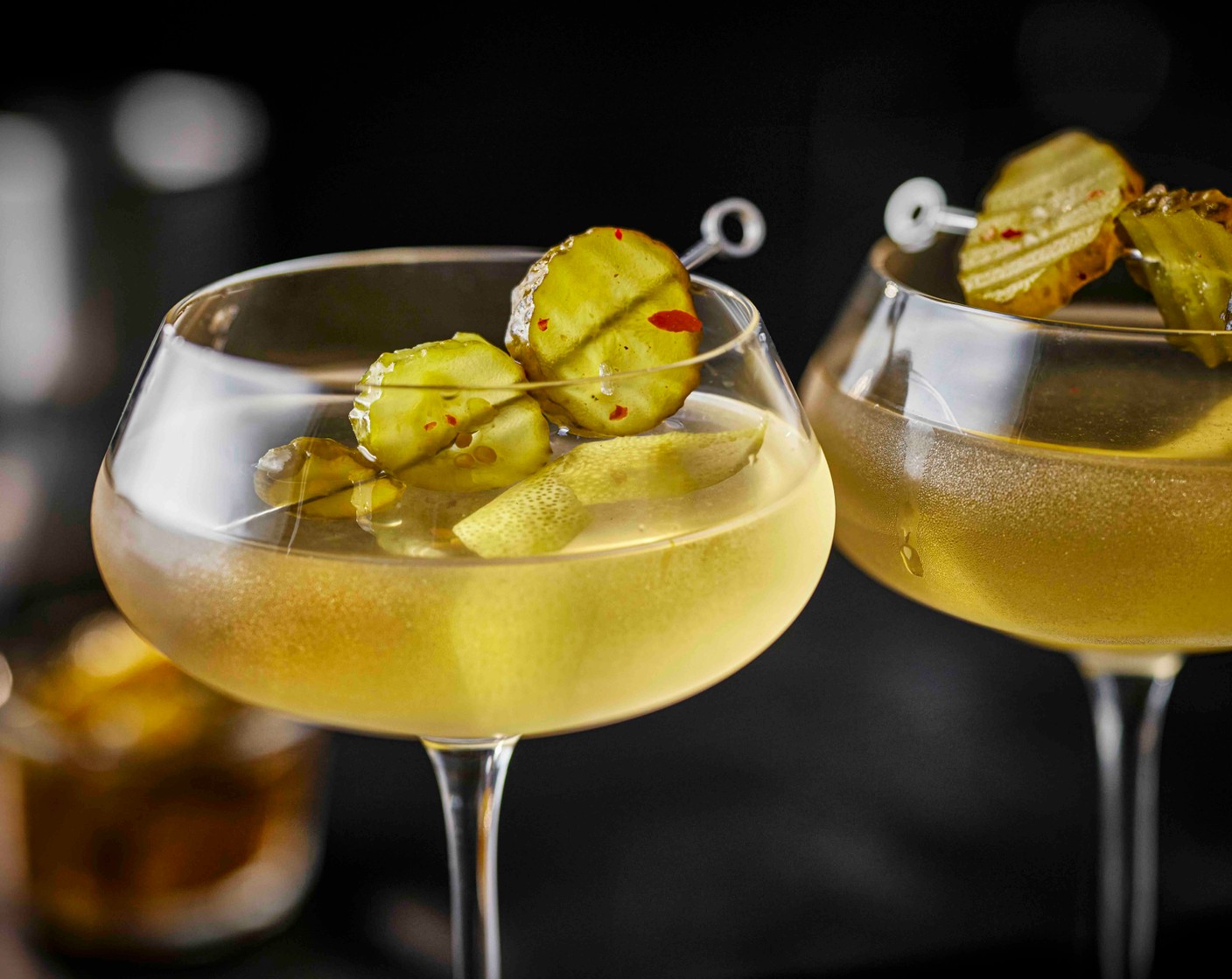 step 3 Strain into the chilled glass, garnish with a strip of lemon zest (1/2) and the fiery pickles (3), threaded onto a cocktail stick.