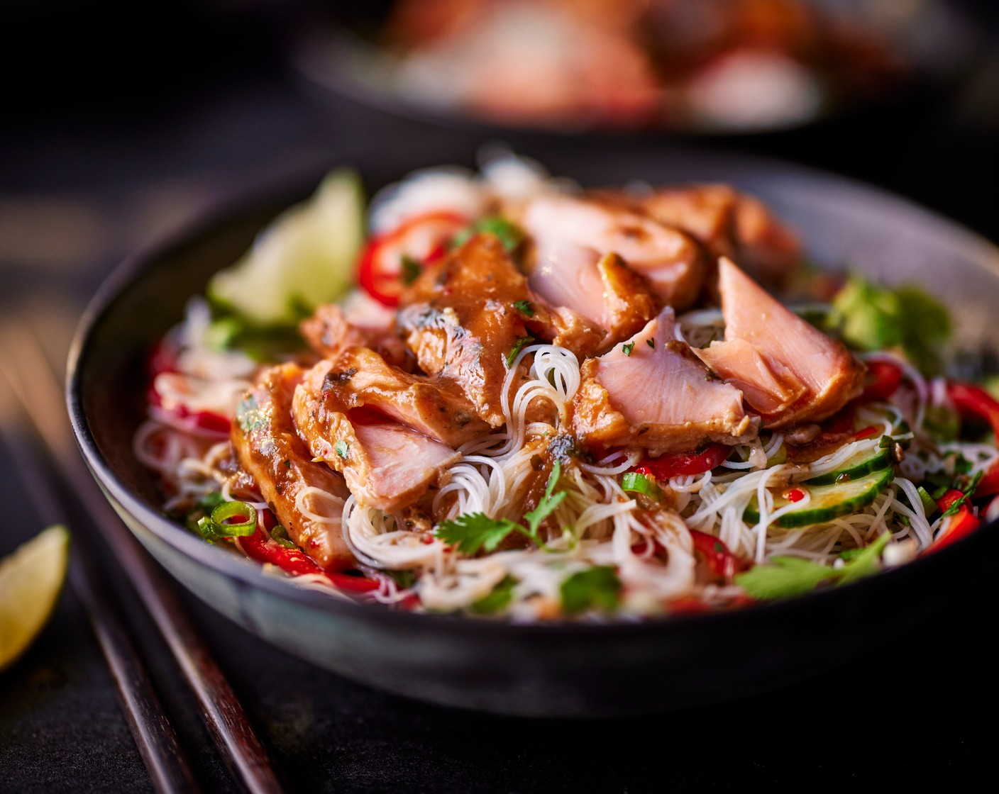 step 5 When the salmon is ready, use a spoon to gently flake it apart, discarding the skin. Serve with the noodle salad, some of the juices from the roasting tray, and the remaining lime (1), cut into wedges. Garnish with a little more fresh coriander.