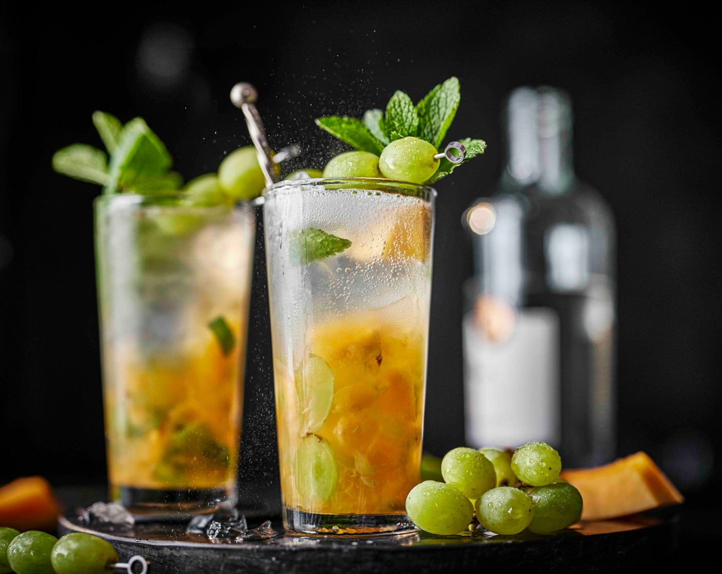 step 1 Muddle the melon (60 g), grapes (30 g), lime juice (30 ml) in a tall glass with the mint (1 handful). Pour in the rum (45 ml) and stir with a long cocktail spoon. Add the ice (1 handful) to the glasses. Top up with the lemon and lime soda (as needed). Thread some grapes onto a cocktail stick to garnish and add a wedge of fresh melon and a few mint leaves.