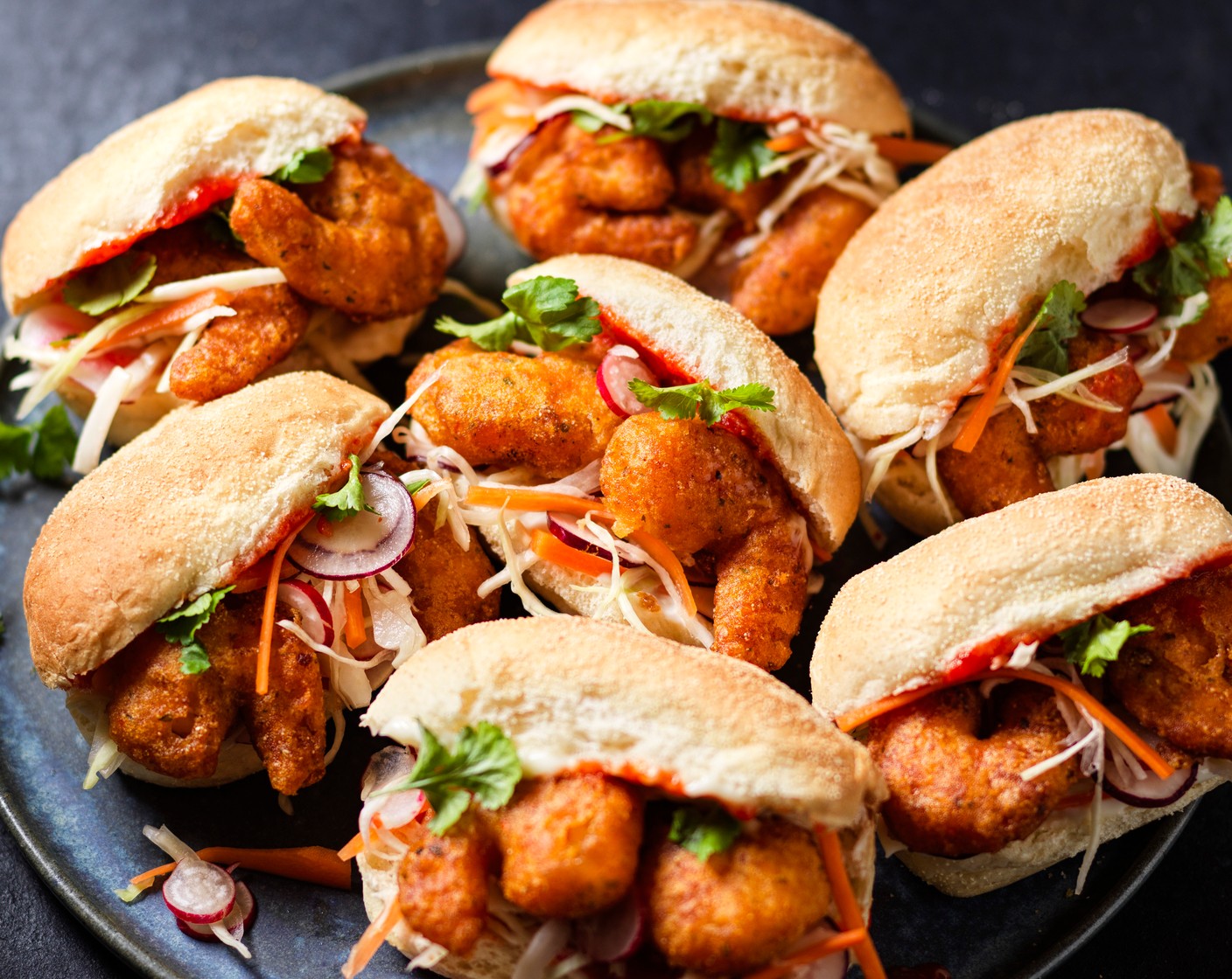 step 3 To assemble, halve the mini submarine rolls (8) and spread one side with mayonnaise (1 tbsp) and the other with sriracha (1 tbsp). Fill each with a small handful of the pickled veg and 2 prawns. Garnish with a little fresh coriander (1 bunch).