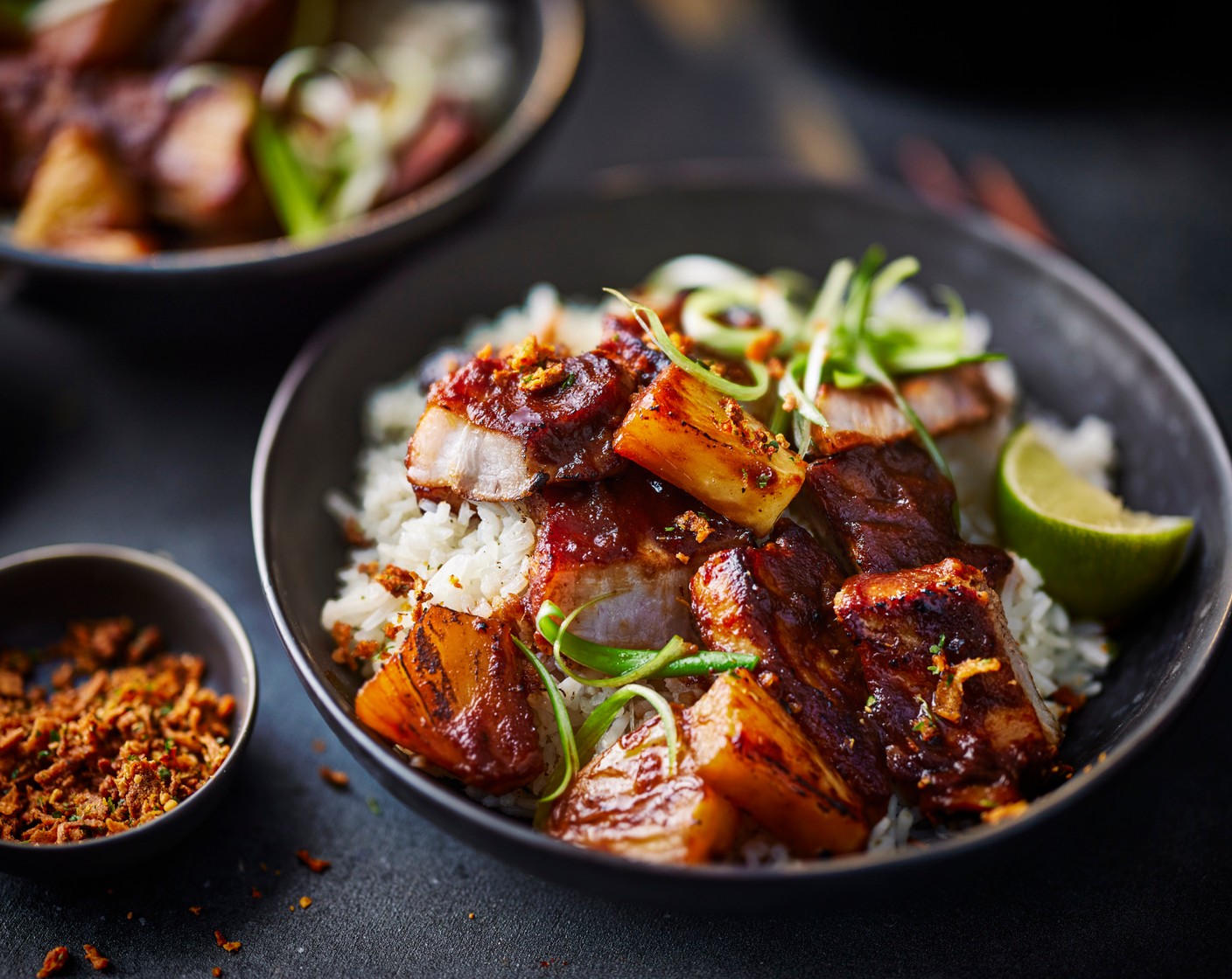 step 6 Serve the pork alongside the rice, topped with spring onions (3), a scattering of chilli topper (to taste) and a wedge of lime (1).