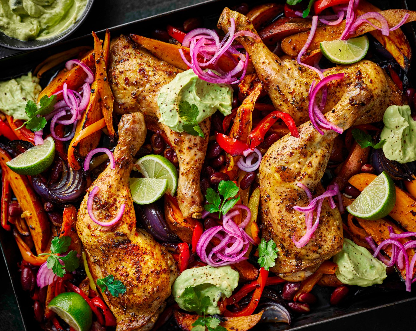 step 7 Serve the traybake topped with the avocado crema and pickled onions. Serve with the remaining lime (1), cut into wedges.