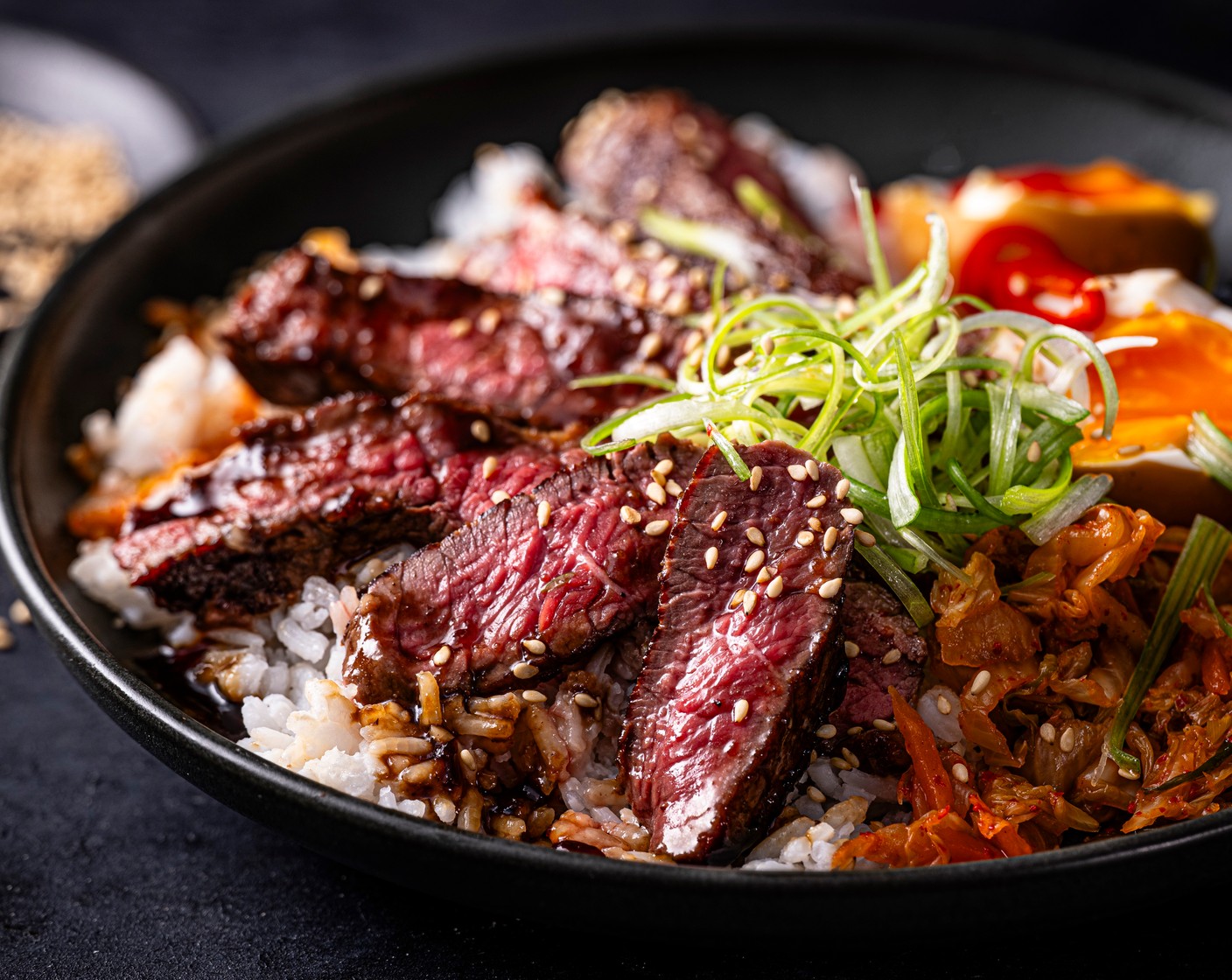 step 6 Serve the rice in bowls, topped with the steak. Pour over the juices from the pan and serve with the marinated eggs, halved, with kimchi (2 tbsp) on the side. Scatter over the remaining spring onions (1) and a sprinkling of the sesame topper.