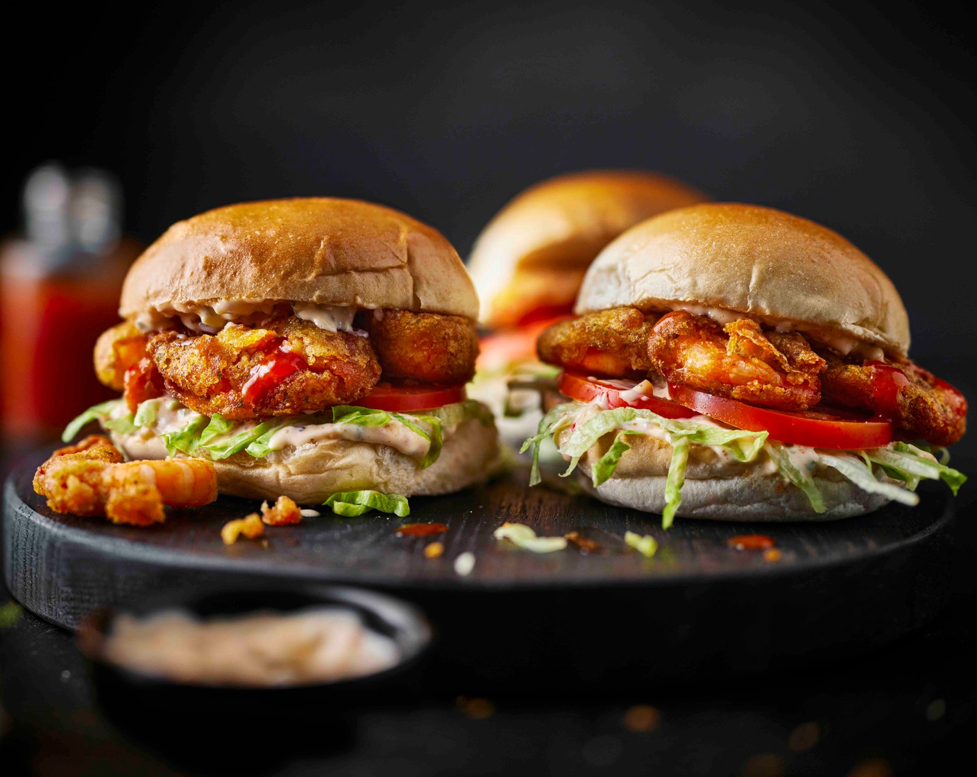 step 4 To assemble the sliders, spread with the Cajun-spiced mayonnaise, then add a small handful of lettuce (1/4) and a slice of tomato (2). Add 2-3 crispy prawns and then drizzle with the Buffalo hot sauce (as needed) and sandwich back together.