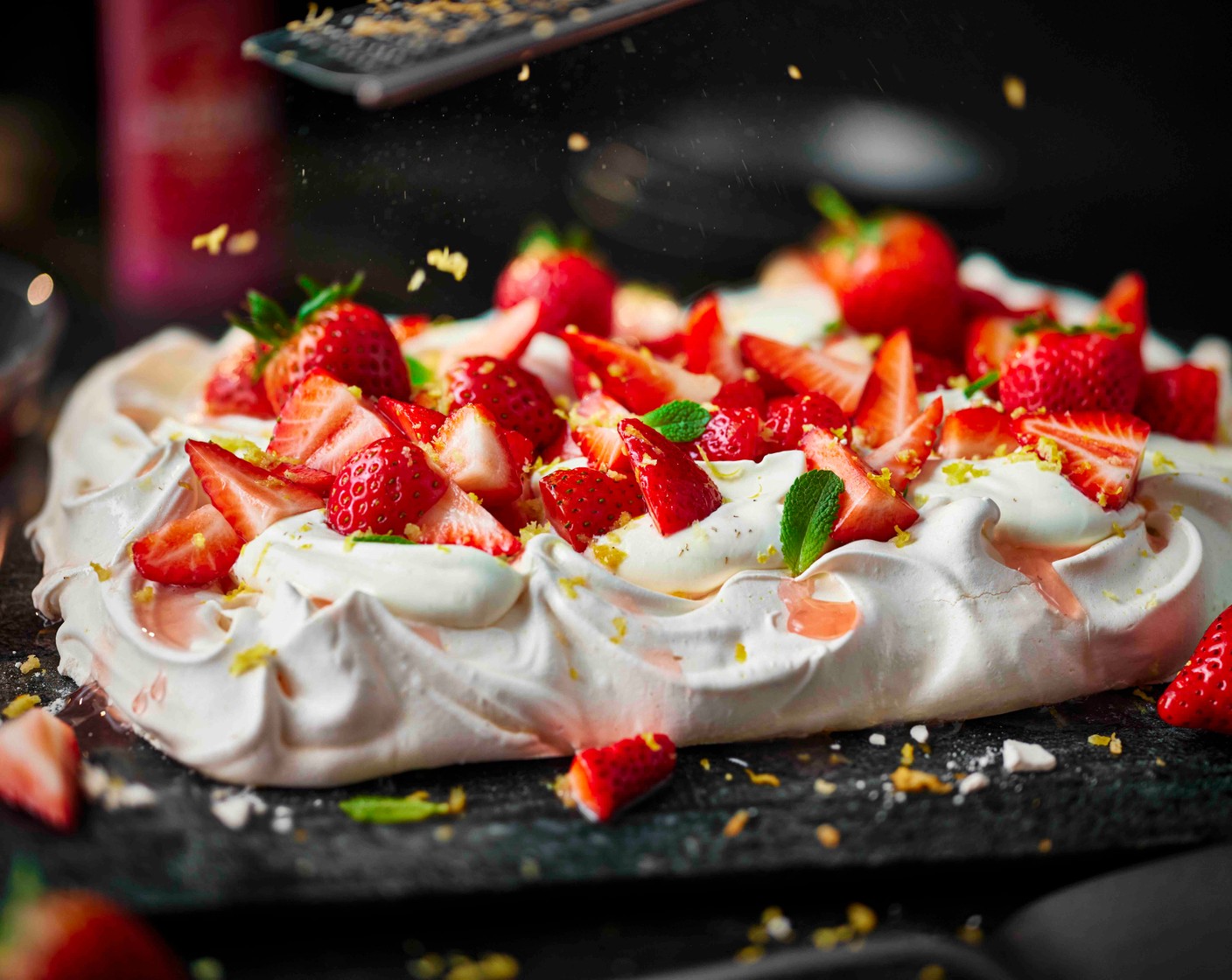 step 5 Combine the cream (400 ml) with 4 tbsp icing sugar (4 tbsp) and whisk until soft peaks form. Spoon over the cooled meringue, followed by the macerated strawberries and the remaining fresh strawberries. Finish with a grating of lemon zest (1) and the remaining mint leaves (2.5 g).