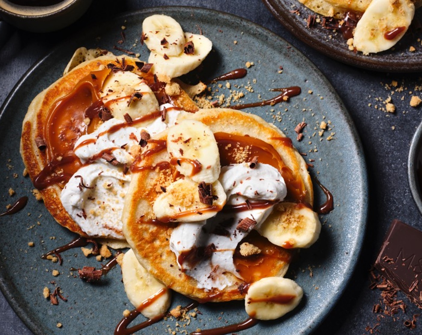 step 3 Spread each pancake with the salted caramel sauce (as needed). Top with yogurt (200 g), banana (2), dark chocolate (as needed) and digestives (2).