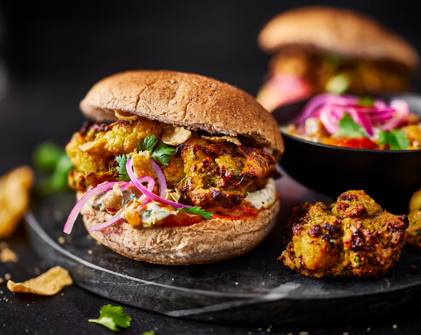 step 6 To assemble, spread the dip (1 pack) over the wholemeal baps (4) and stuff the bhajis inside. Finish with some extra coriander and a handful of crumbled poppadoms (30 g).