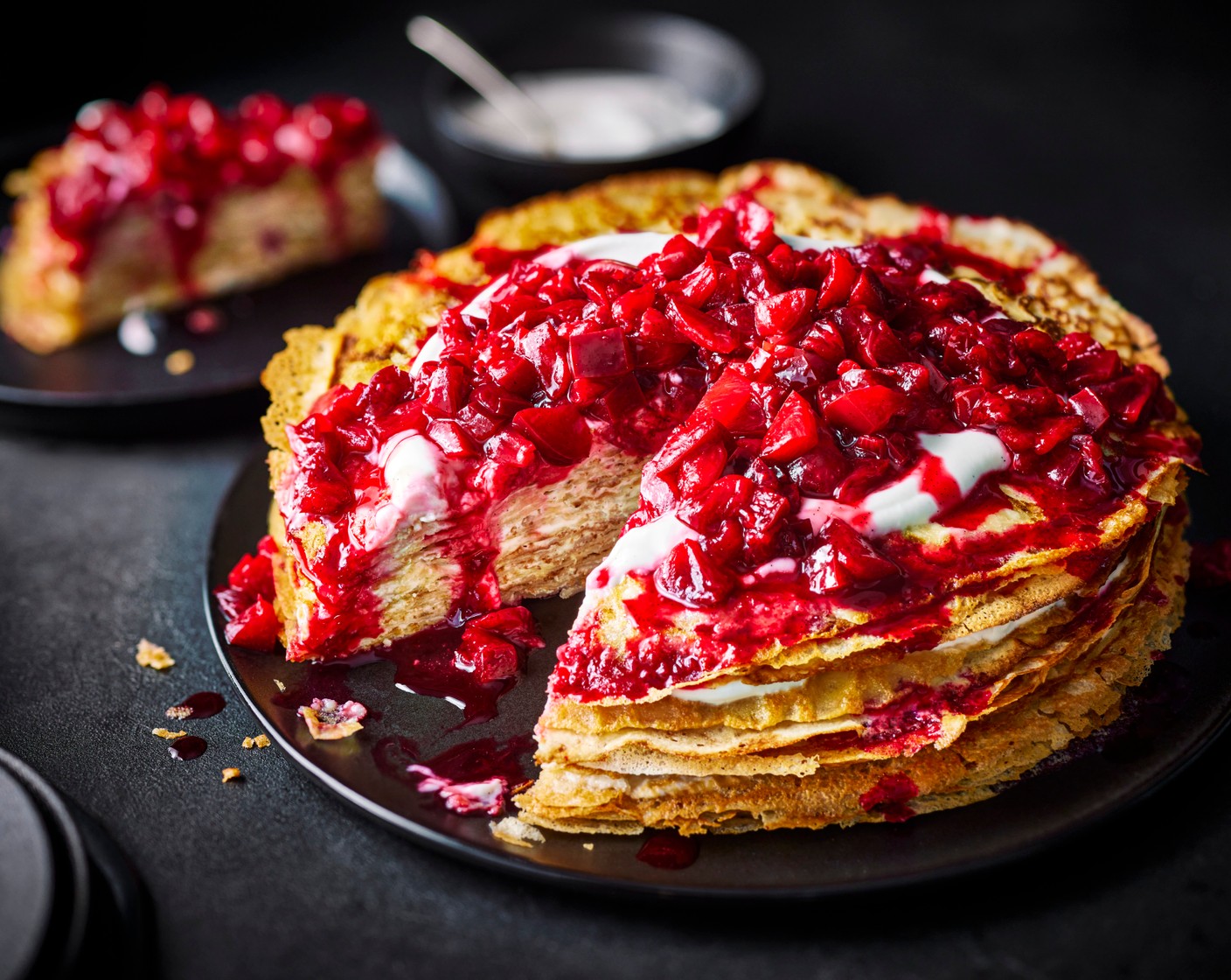 step 6 To assemble, place a crêpe on a large serving plate, put a tablespoon of the vanilla and coconut pot (2 pots) in the middle and spread it evenly using a small palette knife, leaving a small border around the edge. Repeat with the remaining crêpes to create a stack. Carefully drizzle the plum compote on top, then serve.