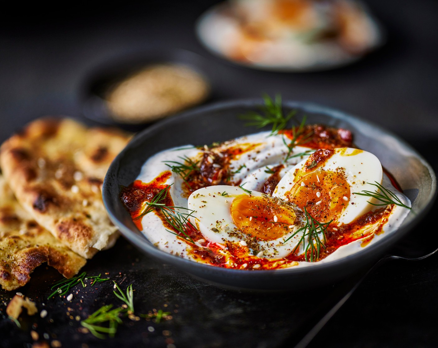 step 5 Spread the yogurt into four bowls, then top each with the halved eggs and a drizzle of harissa butter. Finish with some fresh dill (10 g) and serve with the flatbreads.