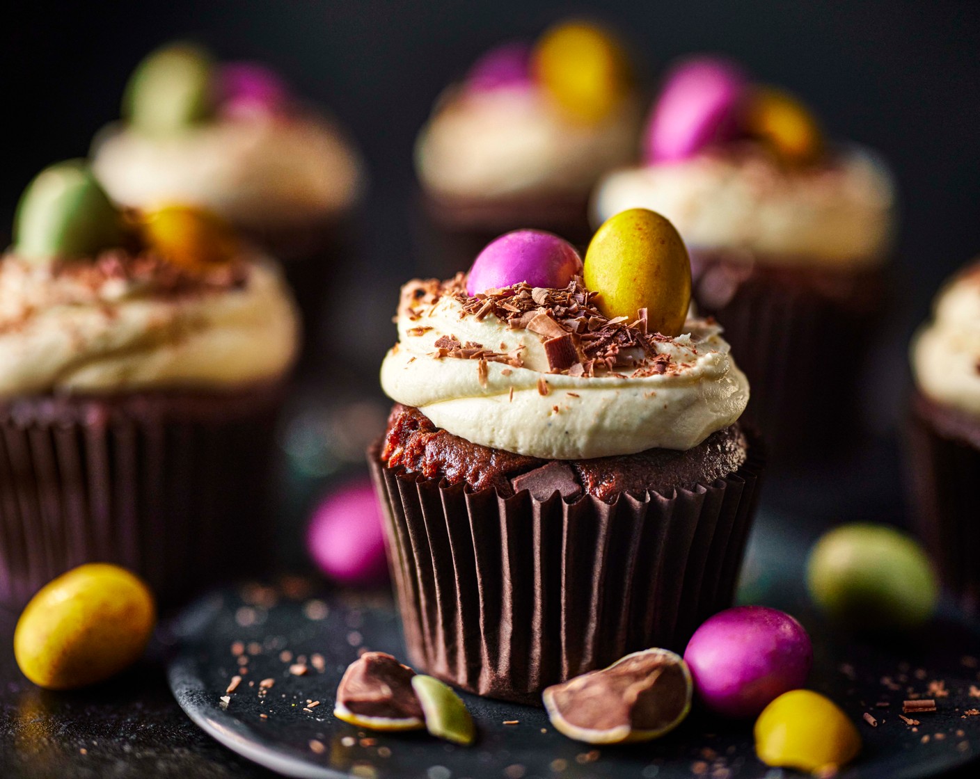 step 4 Once the muffins are cool, use an ice cream scoop or large spoon to add a generous dollop of icing to each one. Make a small dip in the centre of the icing with a teaspoon, nestle in two speckled eggs (50 g) and finish with a sprinkle of shaved milk chocolate (50 g) to create a nest effect.
