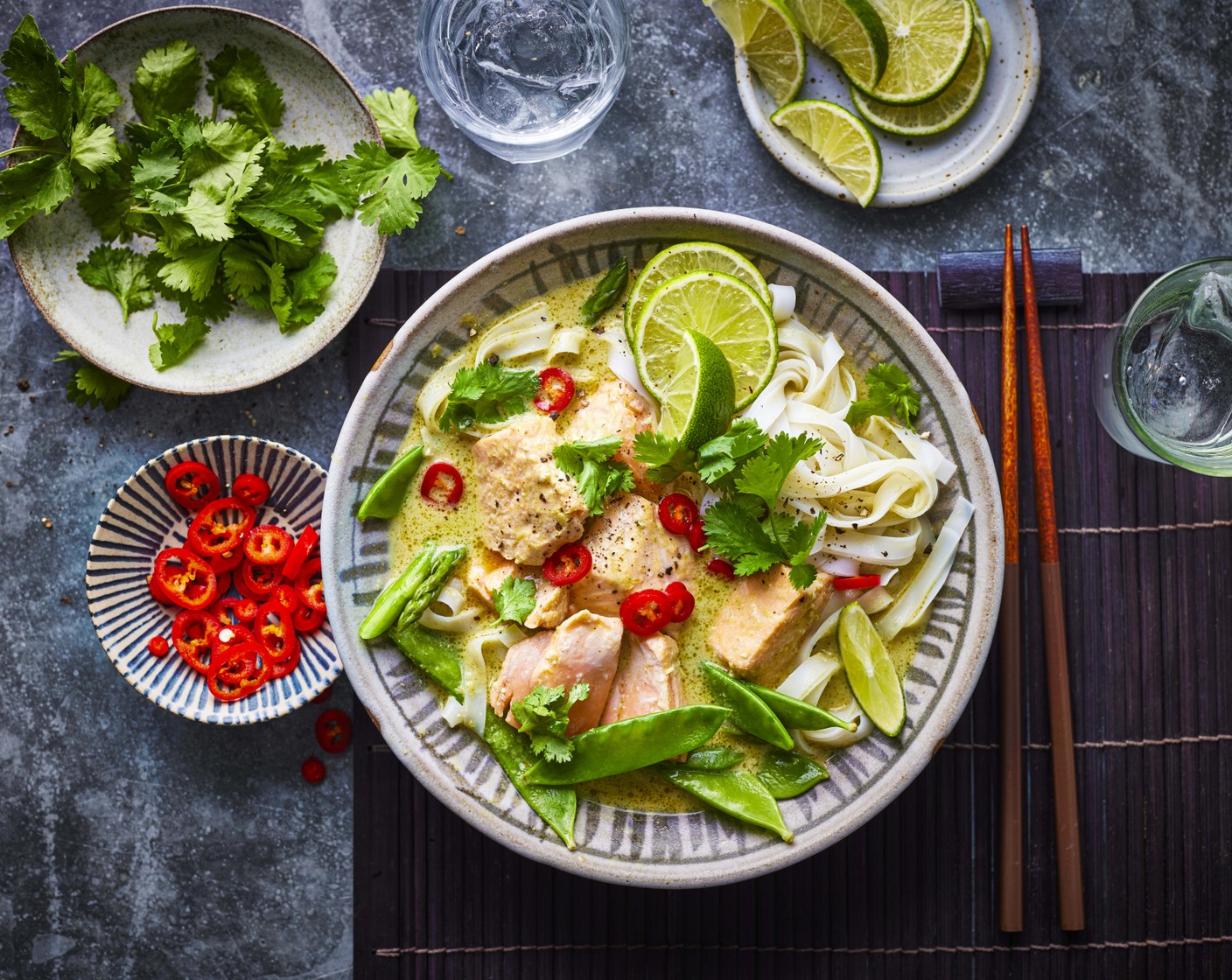 step 6 Pour the rice noodles through a colander and add to the soup to heat through. Spoon into bowls then top with the vegetables and salmon. Garnish with the red chilli (1) and the lime wedges (1) to serve.