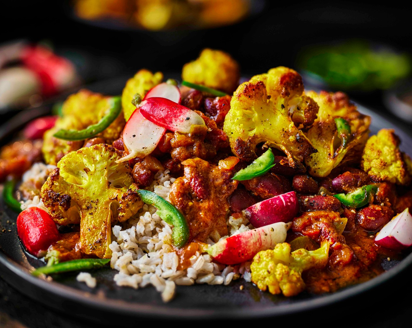 step 5 Finish the roasted cauliflower with the zest and juice of 1 lime (1). Spoon the rice into bowls, top with the kidney bean curry, roasted cauliflower and pickled radishes, and scatter over the remaining sliced green chilli (1).