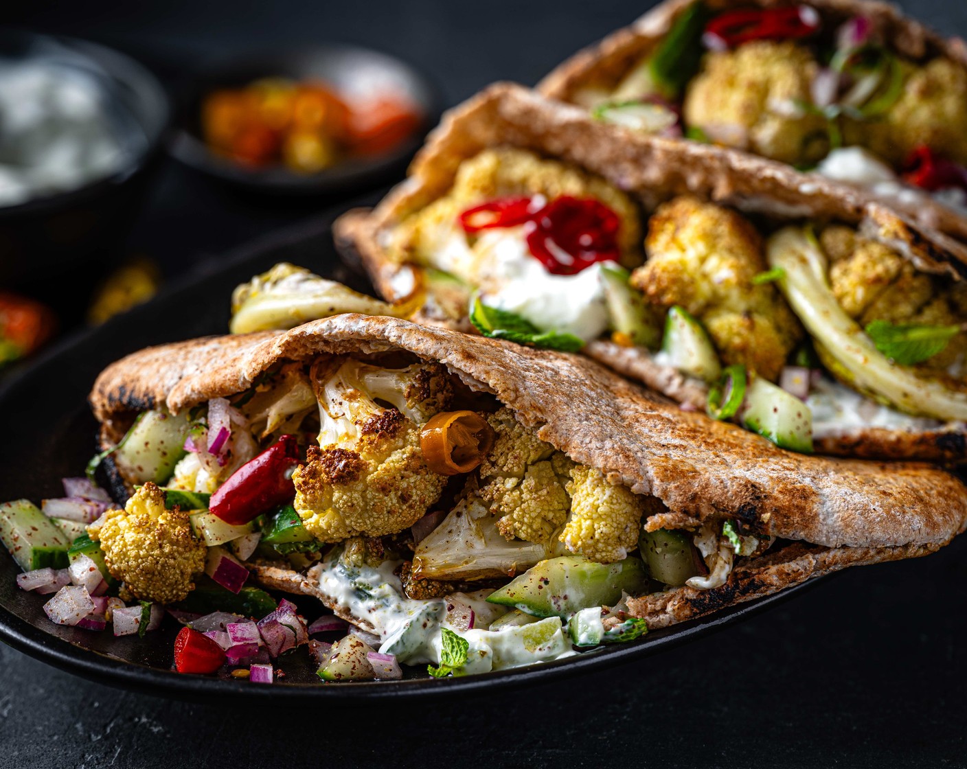 step 5 Fill the pitta breads with a dollop of tzatziki (1 tub), some of the crunchy salad, and the roasted cauliflower. Finish with a pickled chilli (60 g), if you like.