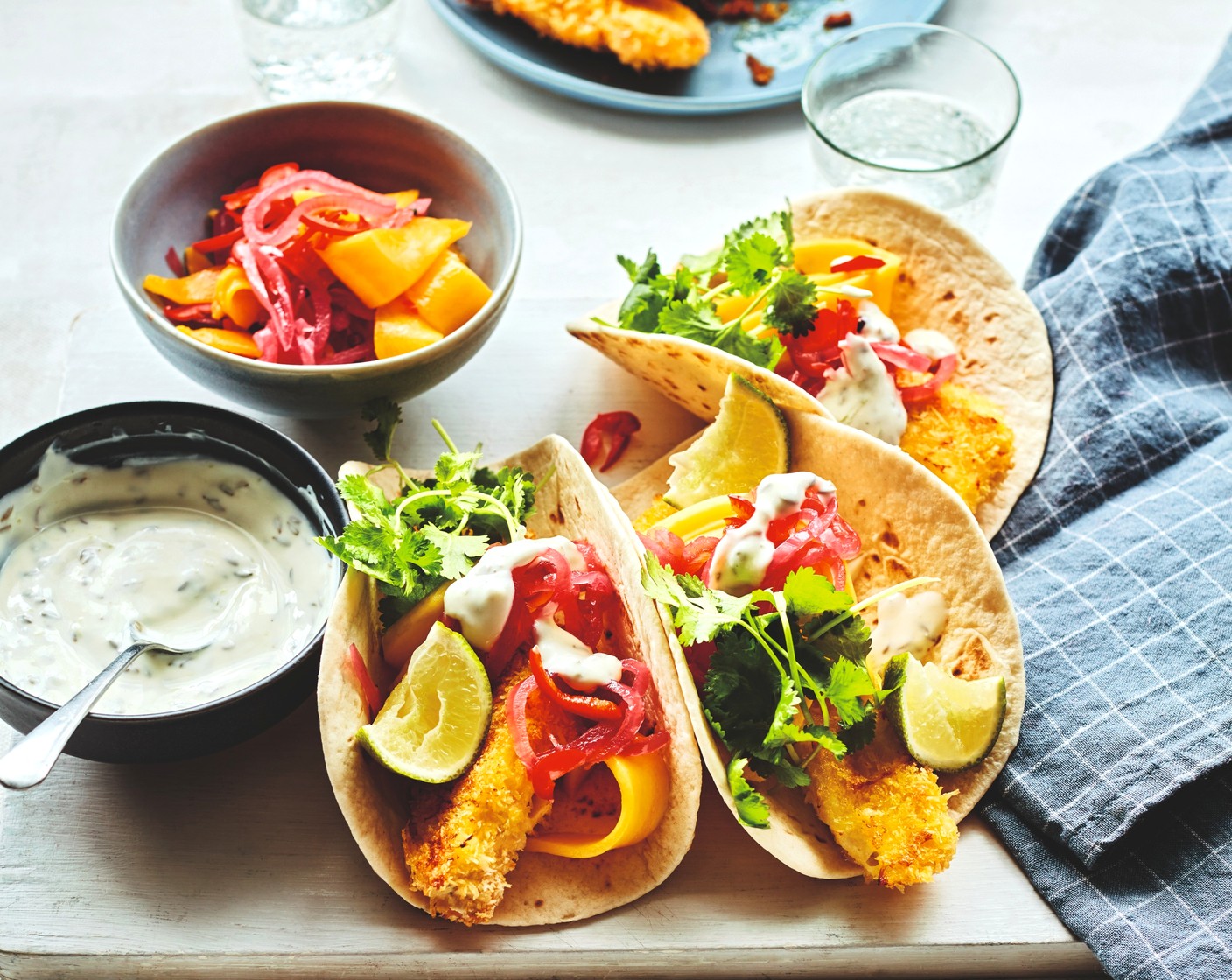 step 6 Warm the M&S soft taco wraps (8) according to the pack instructions. Top each with the goujons and mango salsa. Divide between serving dishes and finish each with a drizzle of the yogurt dressing, a scattering of coriander (1 handful) and a lime wedge (1) for squeezing.