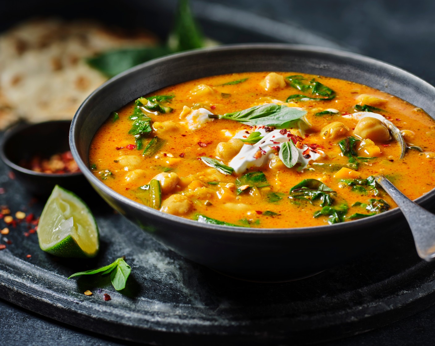 step 5 Serve the soup in bowls, topped with a dollop of yogurt (4 tbsp) and a sprinkle of chilli flakes (1 tsp), with the flatbreads on the side, with a handful of Thai basil (1 handful) scattered on top.