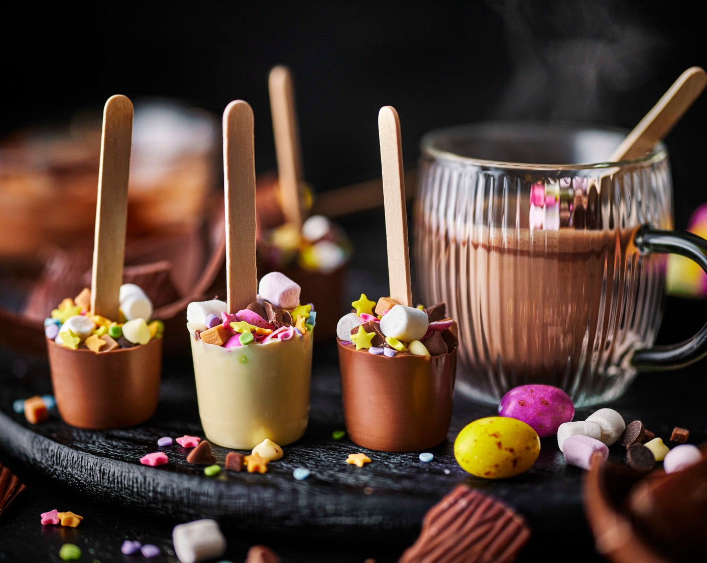 step 6 To make the hot chocolate, warm the milk (800 ml) in a pan until steaming. Pour into 6 cups and stir in a chocolate stirrer until melted.